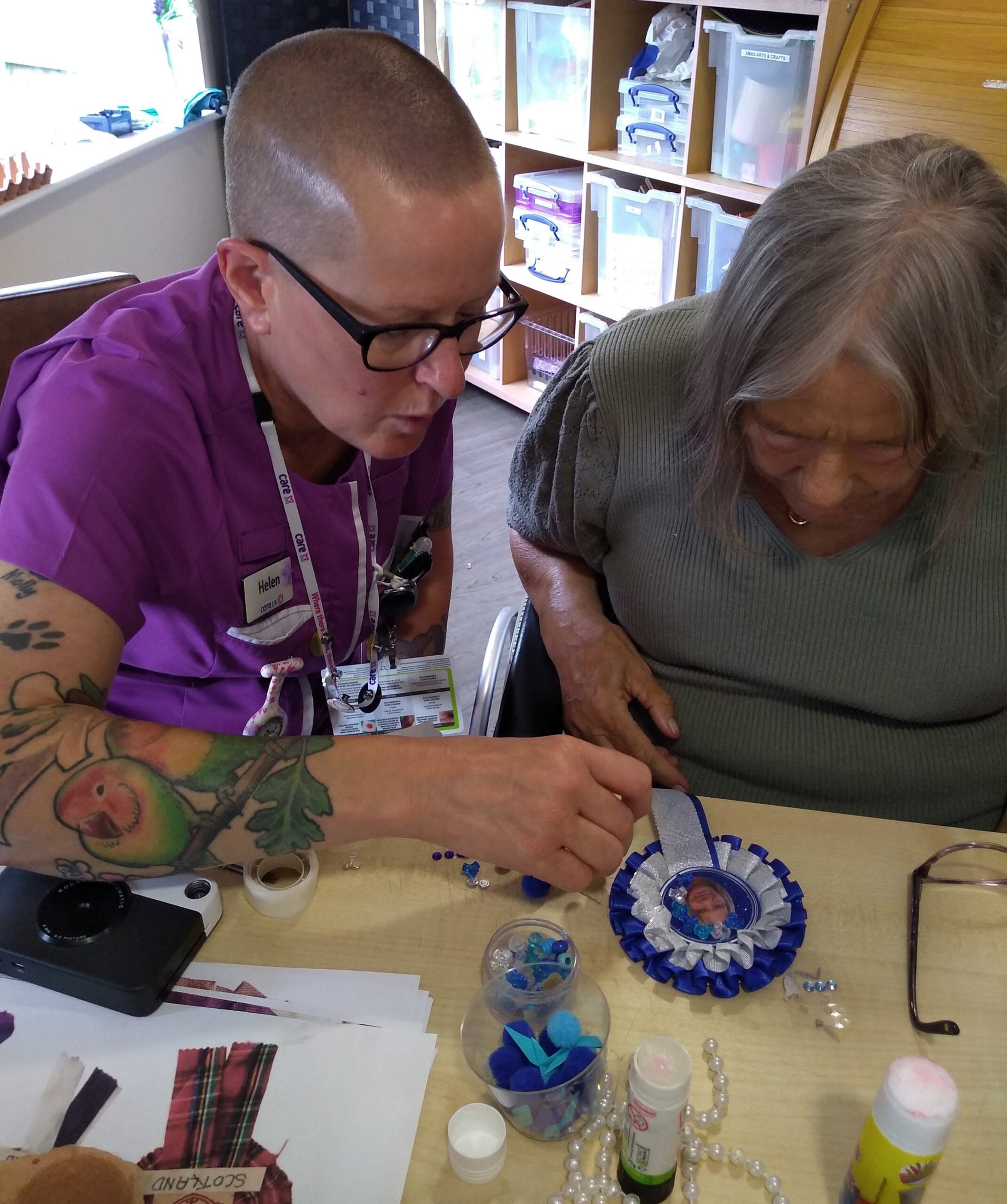 A care worker and participant making a rosette together