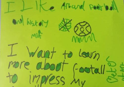 Hand written notes on a green piece of paper saying I like art and football and history and I want to learn more about football to impress my family aka brother