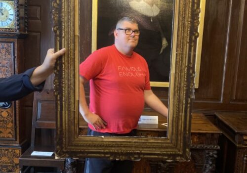 A Brave Art student poses behind a portrait frame