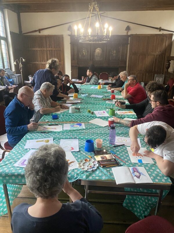 Brave Art students, seated at a long table, sketching intently