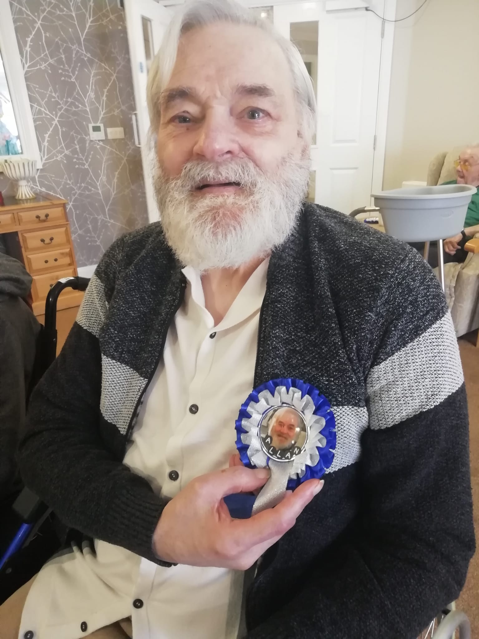 Gentleman wearing a blue and white rosette decorated with an image and other details