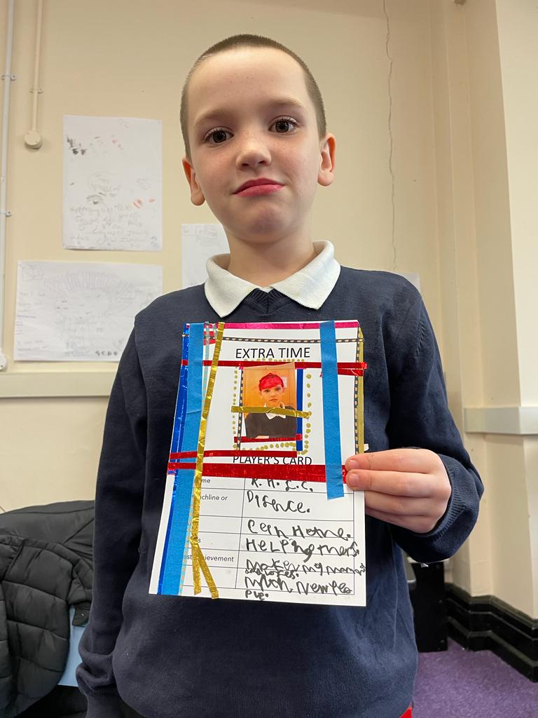 A school pupil holding his Extra Time Player's card, decorated with coloured strips and a photograph of himself