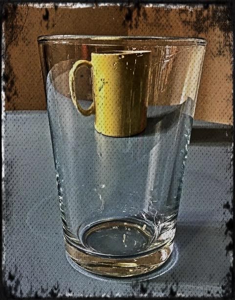 A digital image of a yellow mug is seen through a transparent glass jug in the foreground. Affects have been applied to the image making it look more like something painted than photographed.