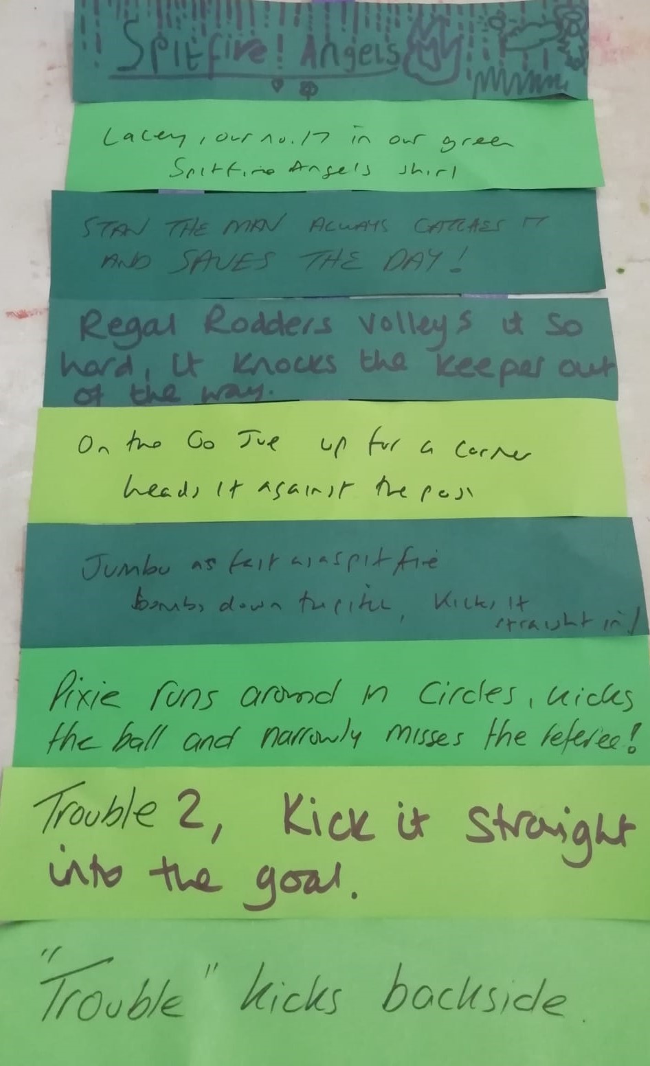 A series of strips of green paper stuck together, each strip with a hand written line of verse on it referencing football