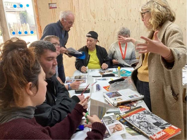 Brave artists and staff work together around a table, studying books and art works,