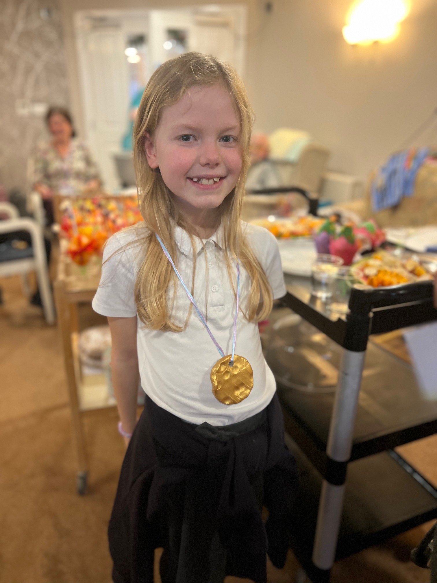 A schoolgirl wearing a gold painted medal with a light blue ribbon