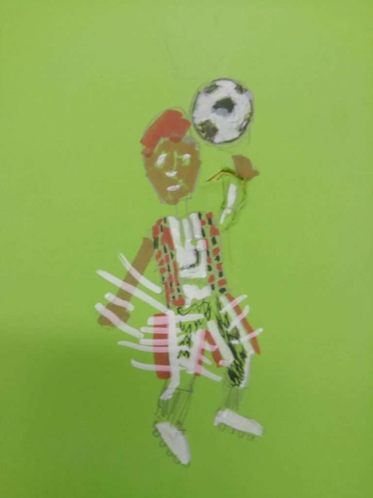 A cartoon of a footballer with red hair, wearing red, black and white kit and white boots, flicking a black and white ball in the air