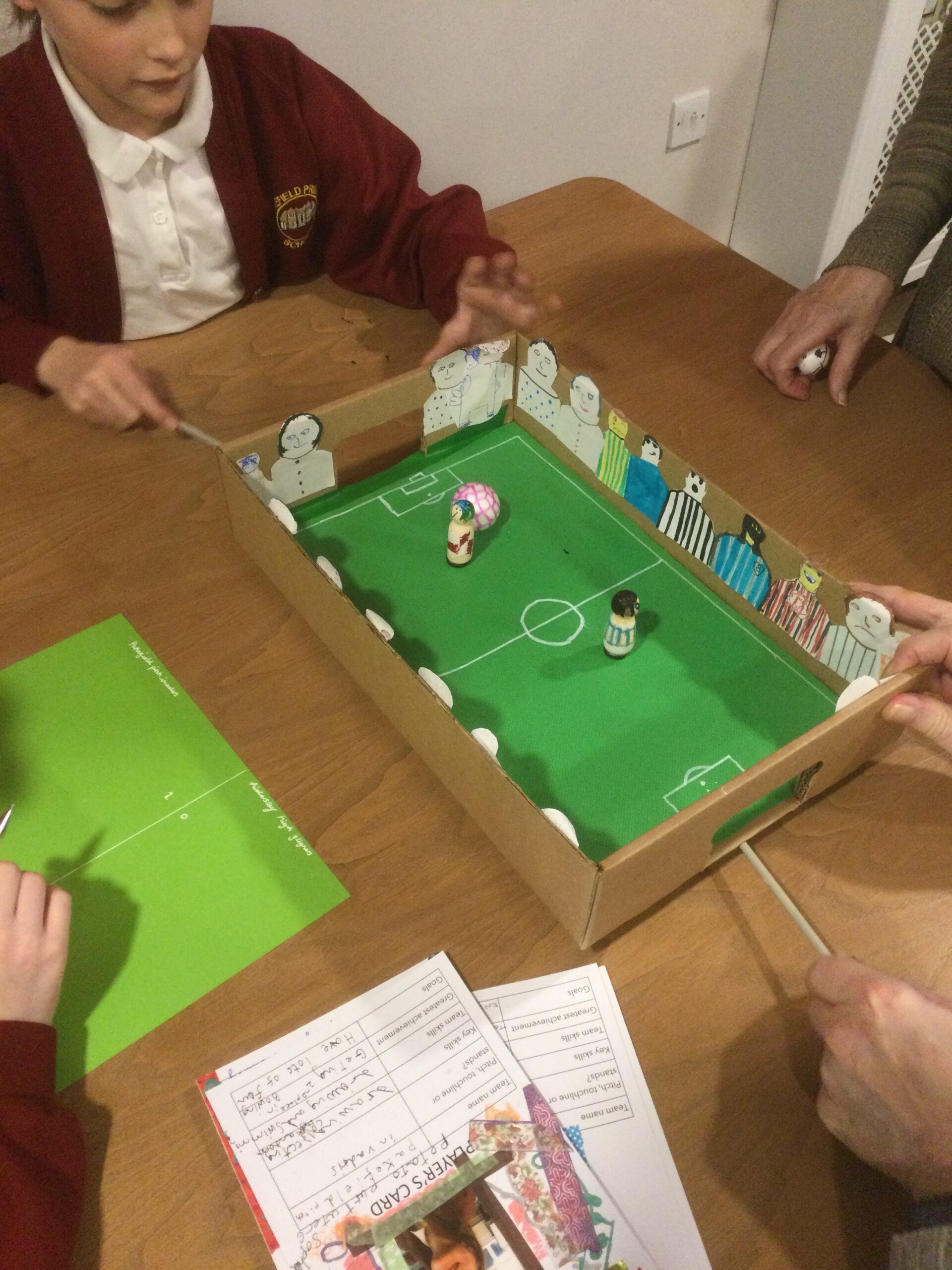 Overhead view of a cardboard football game showing two players and a pink and white ball