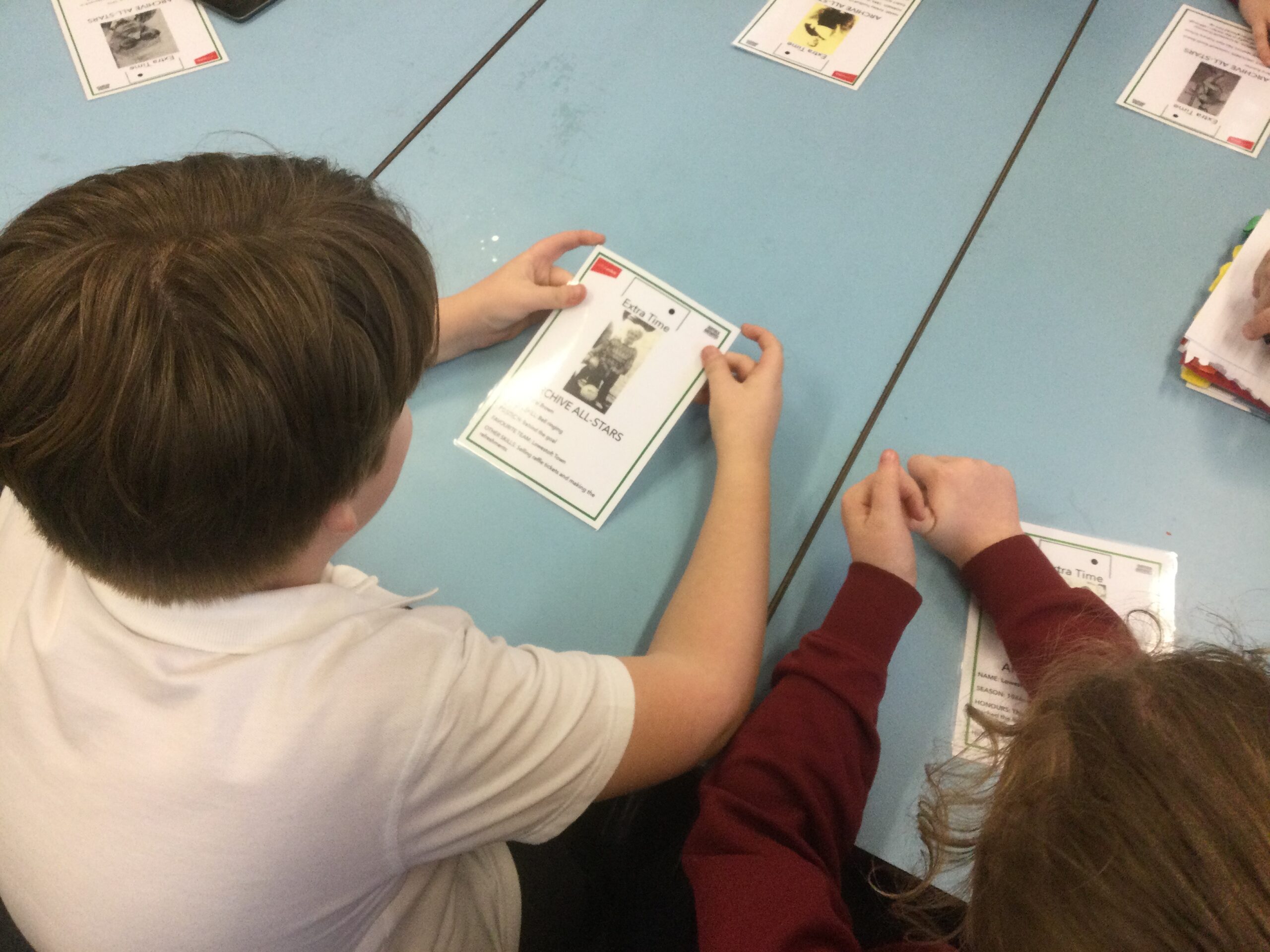 Overhead shot of children looking at laminated cards about football in Lowestoft