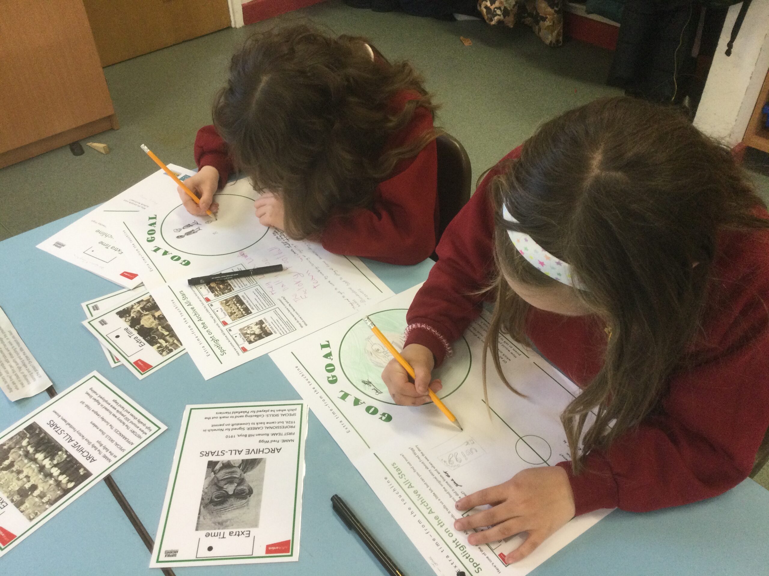 Two school girls using pencil to write on their worksheets