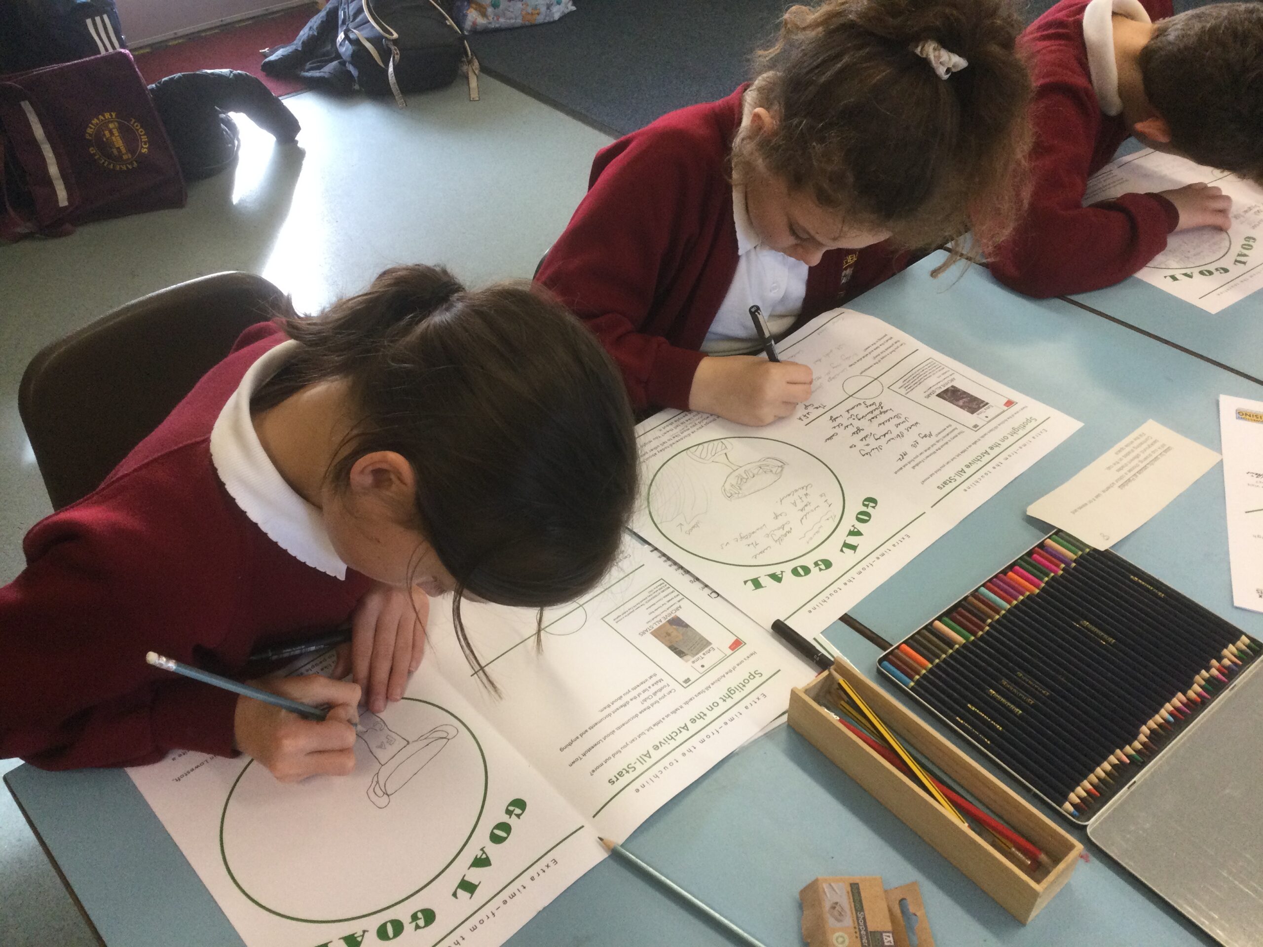 School children seated in a row working on their drawings