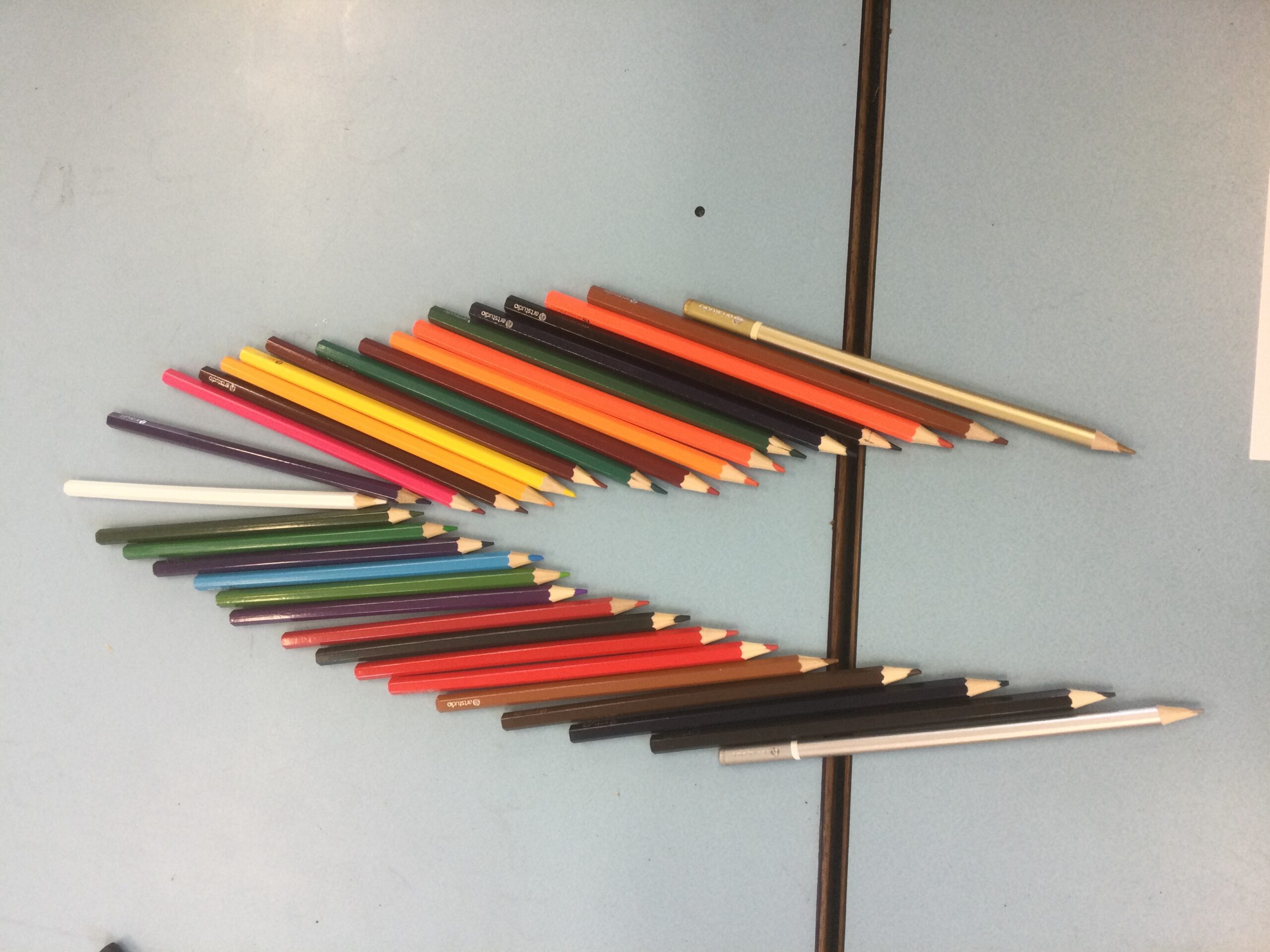 A collection of coloured pencils laid out in a chevron shape