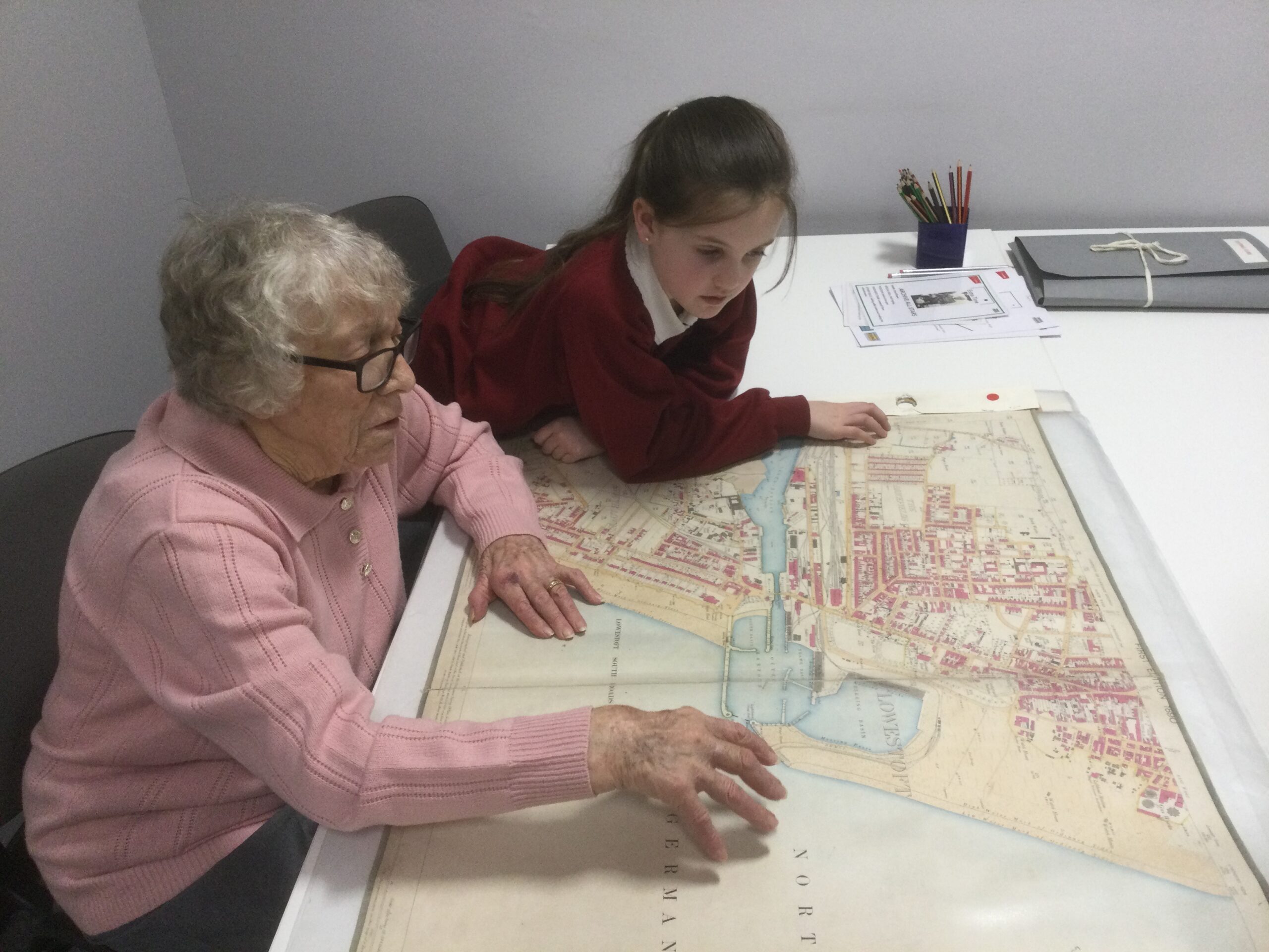 A school girl and woman looking intently at a street map of the town