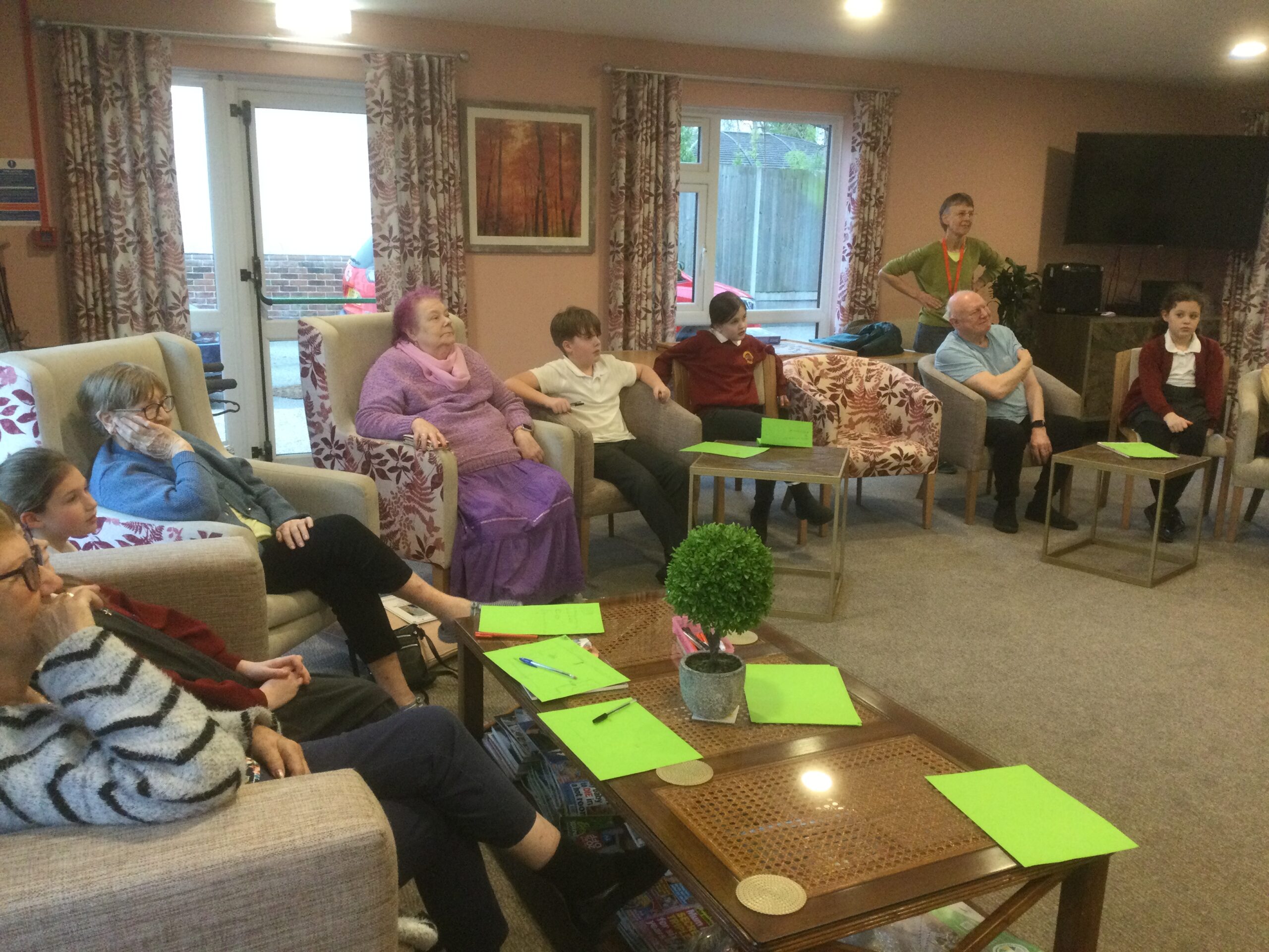 A mixed group of adults and children all staring at someone out of camera shot