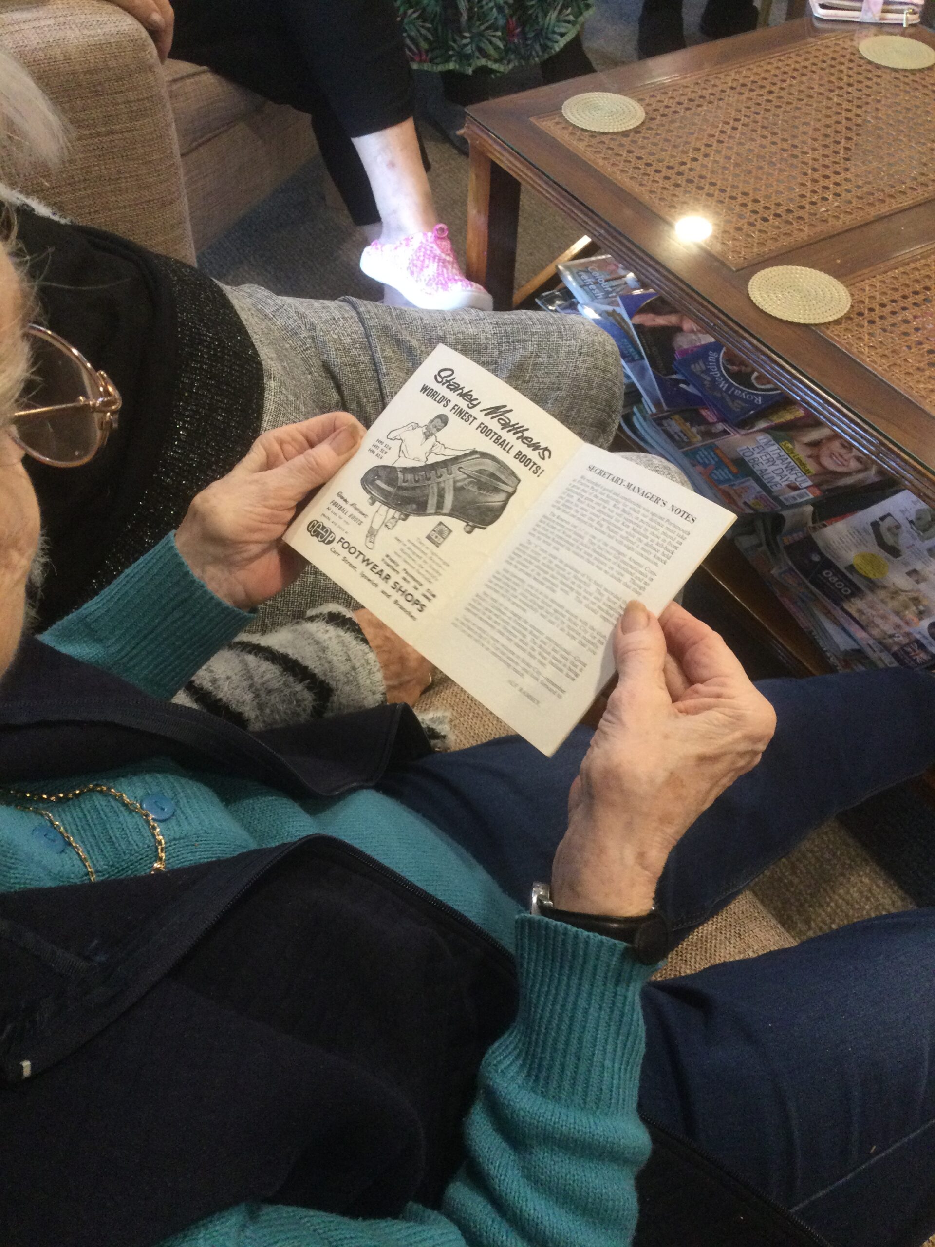 An overhead view of a person looking at a leaflet showing an advert for football boots