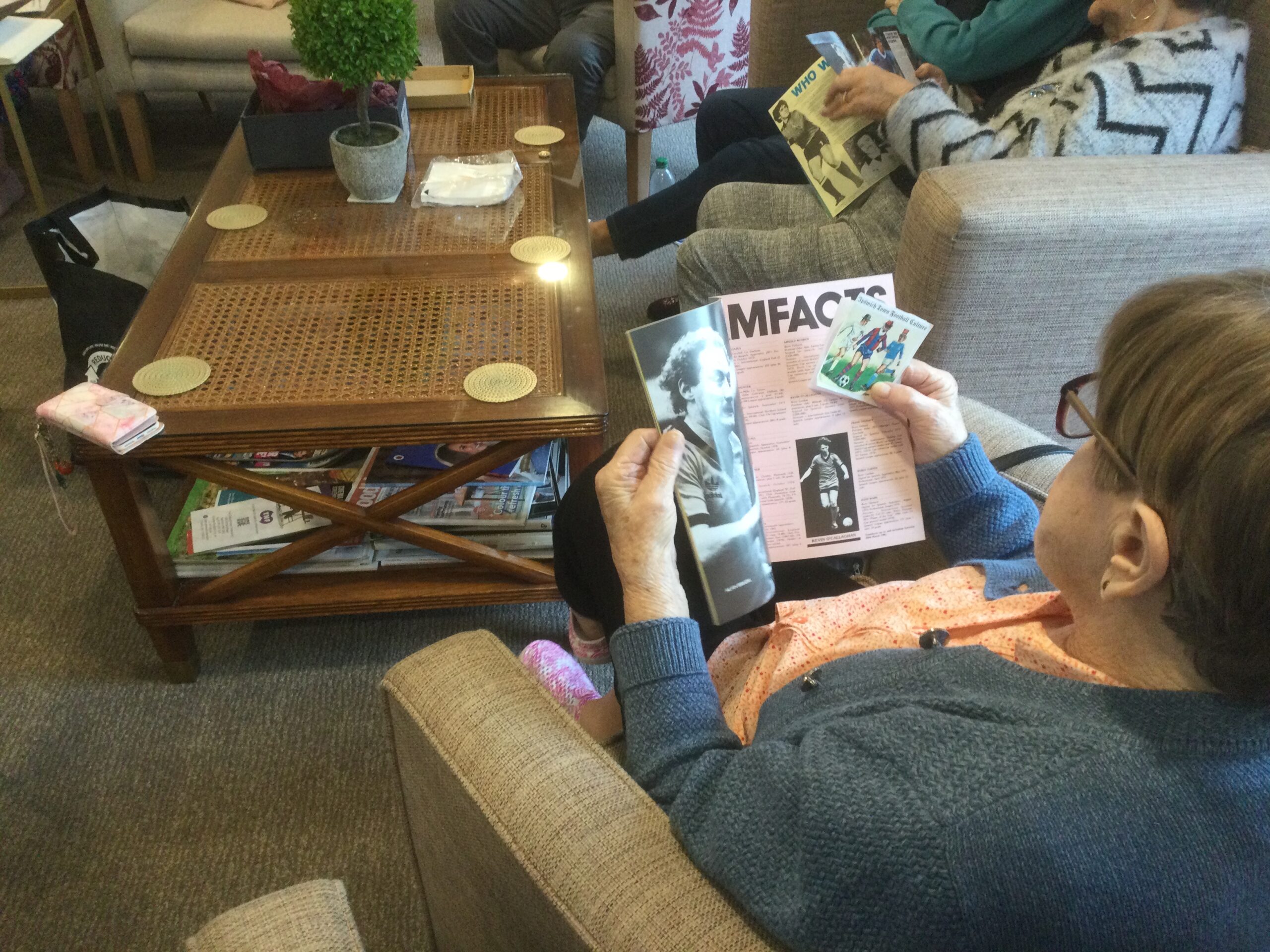 A view over a person's shoulder as she she reads an article in a football programme