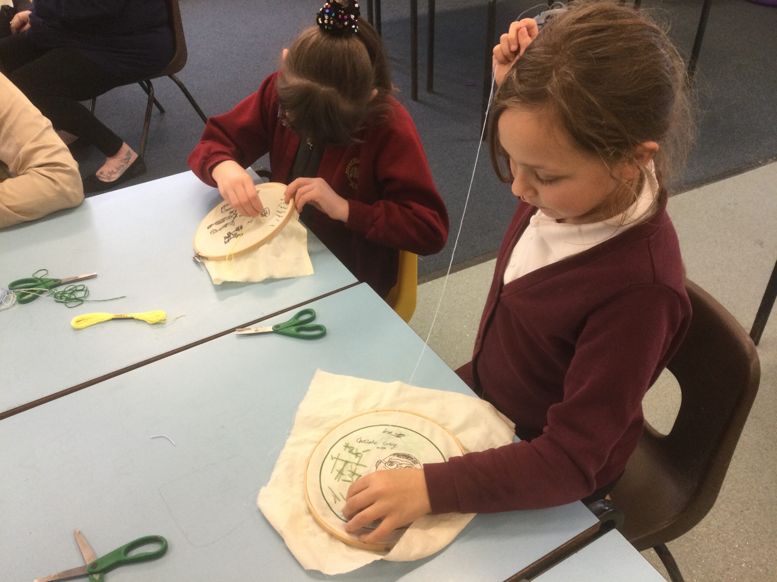 Two school girls embroidering pieces of fabric