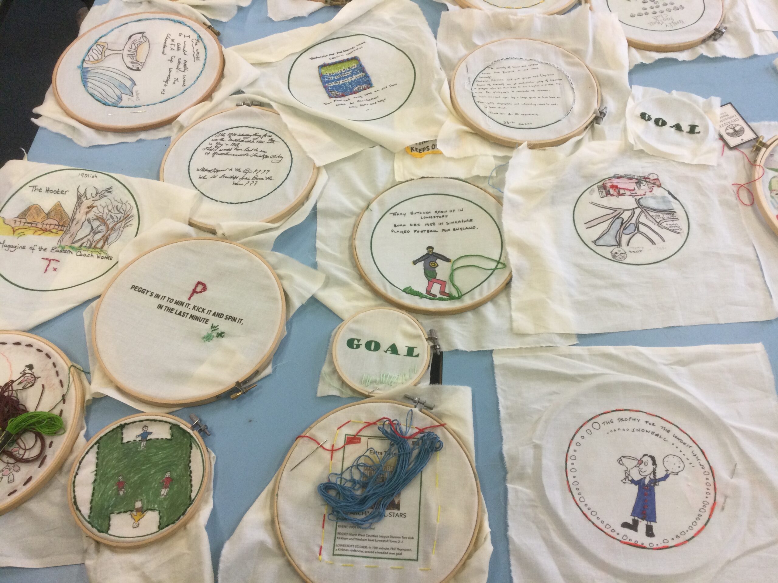 A number of pieces of printed fabric, held in wooden embroidery hoops, some of them already stitched