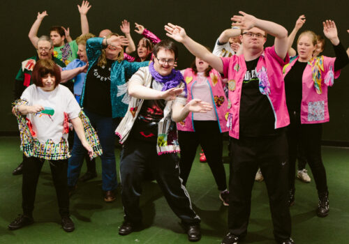 Brave Art students celebrate in the finale of their end of year show by dancing and waving their arms above their heads.