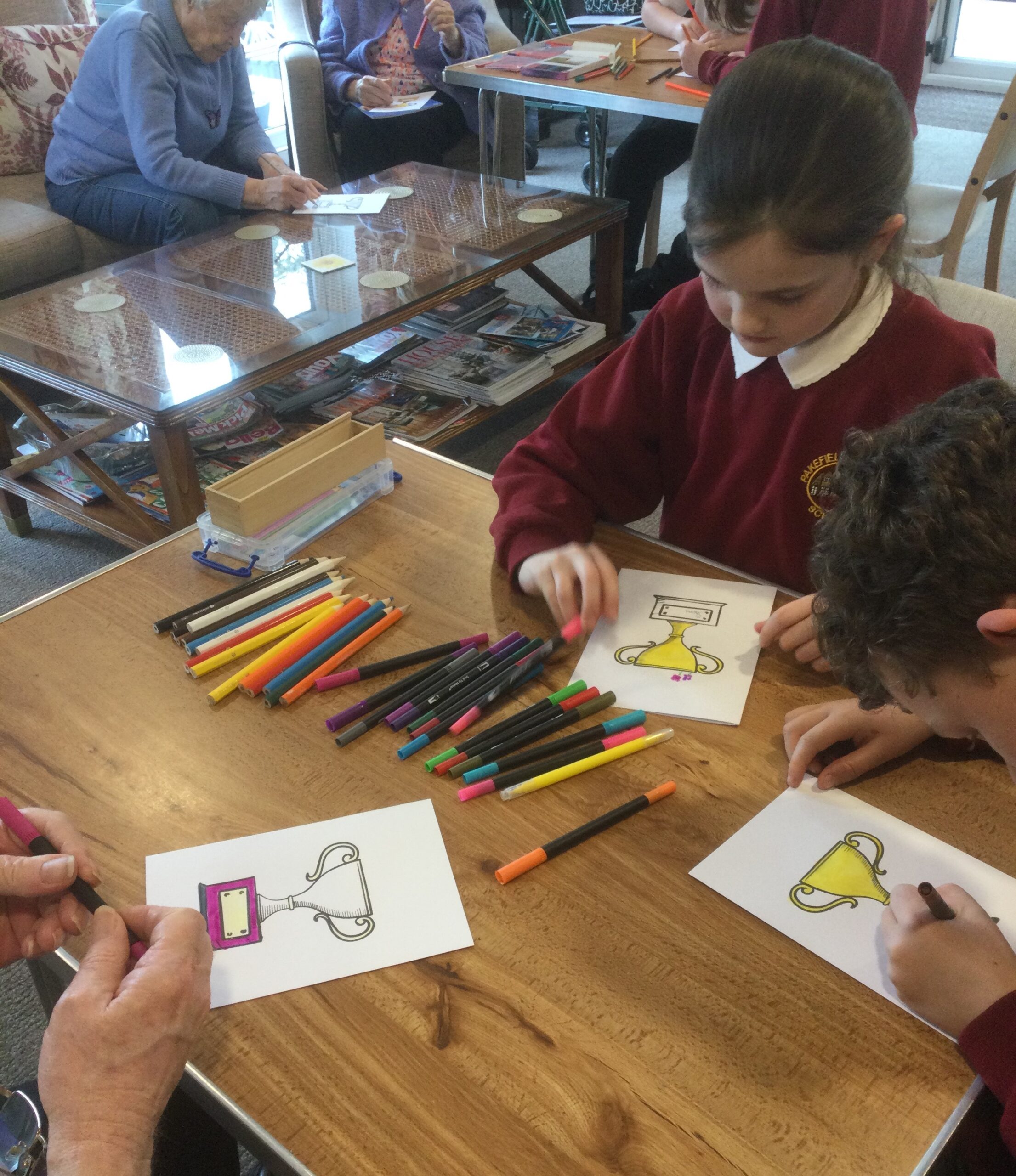 Children colouring in white cards with a printed trophy on the front