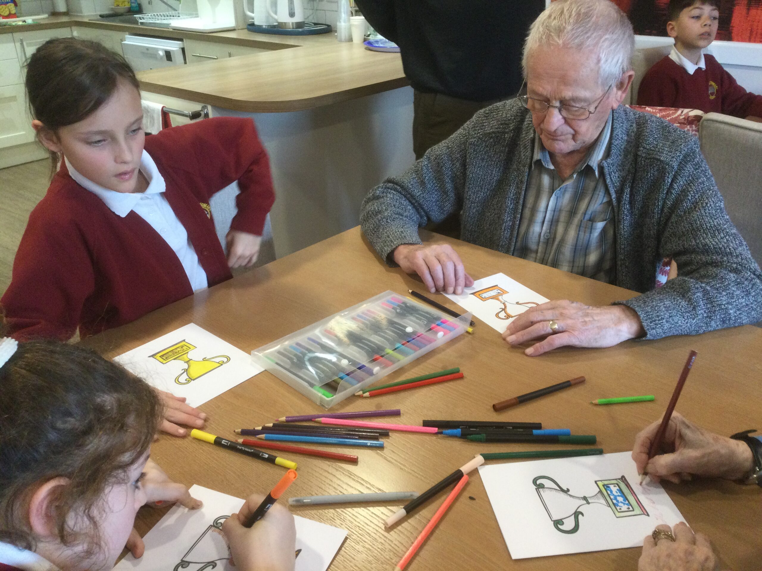 A mixed group of adults and children colouring in cards