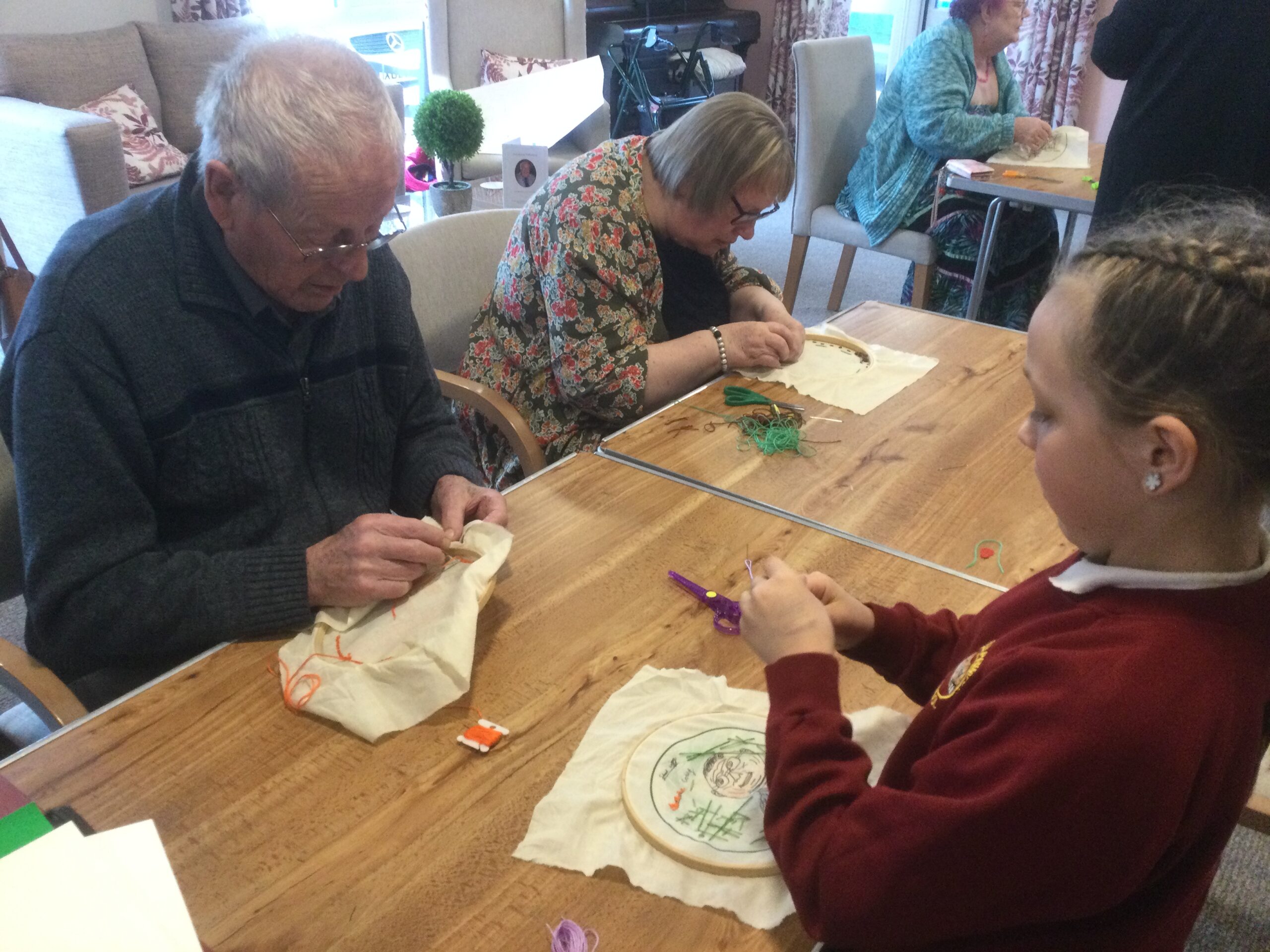 Adults and a school child concentrating on stitching pictures