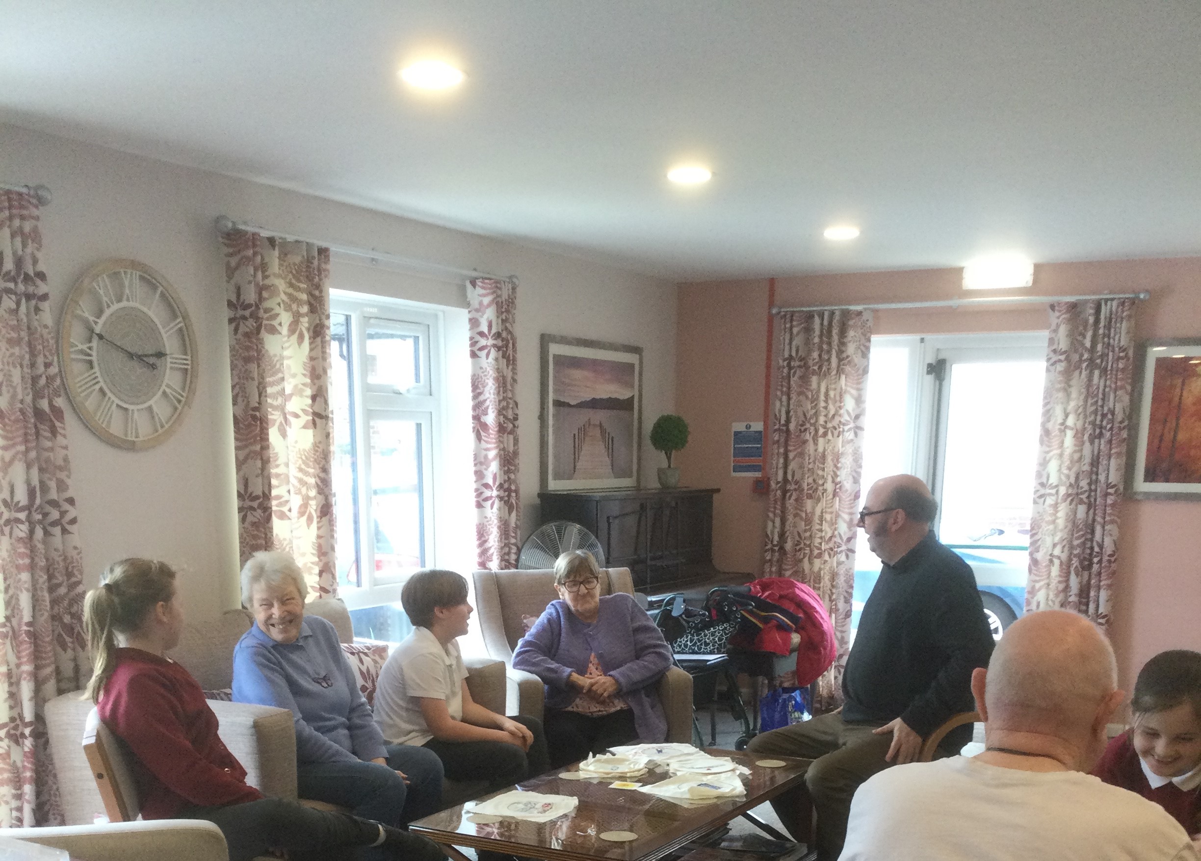 A mixed group of adults and children seated round a coffee table chatting to one another