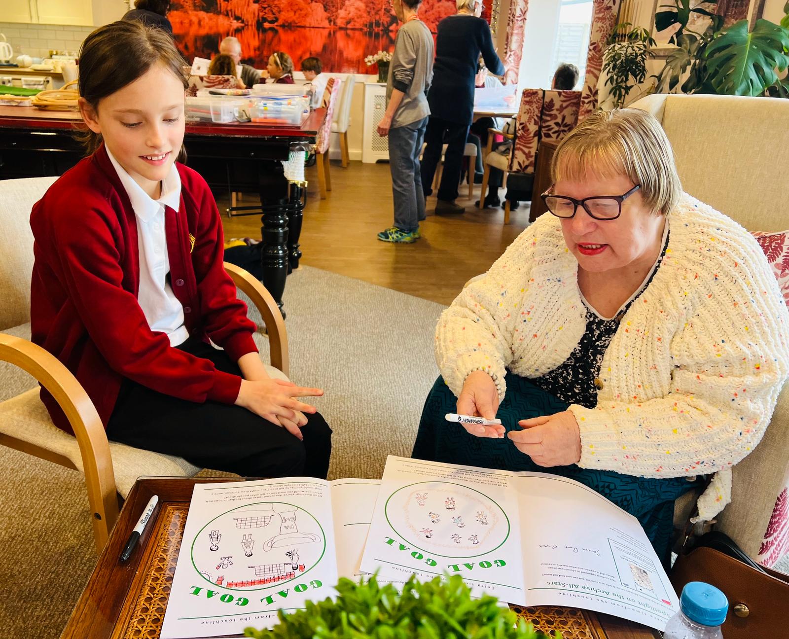 An adult and child seated side by side chatting about their work together