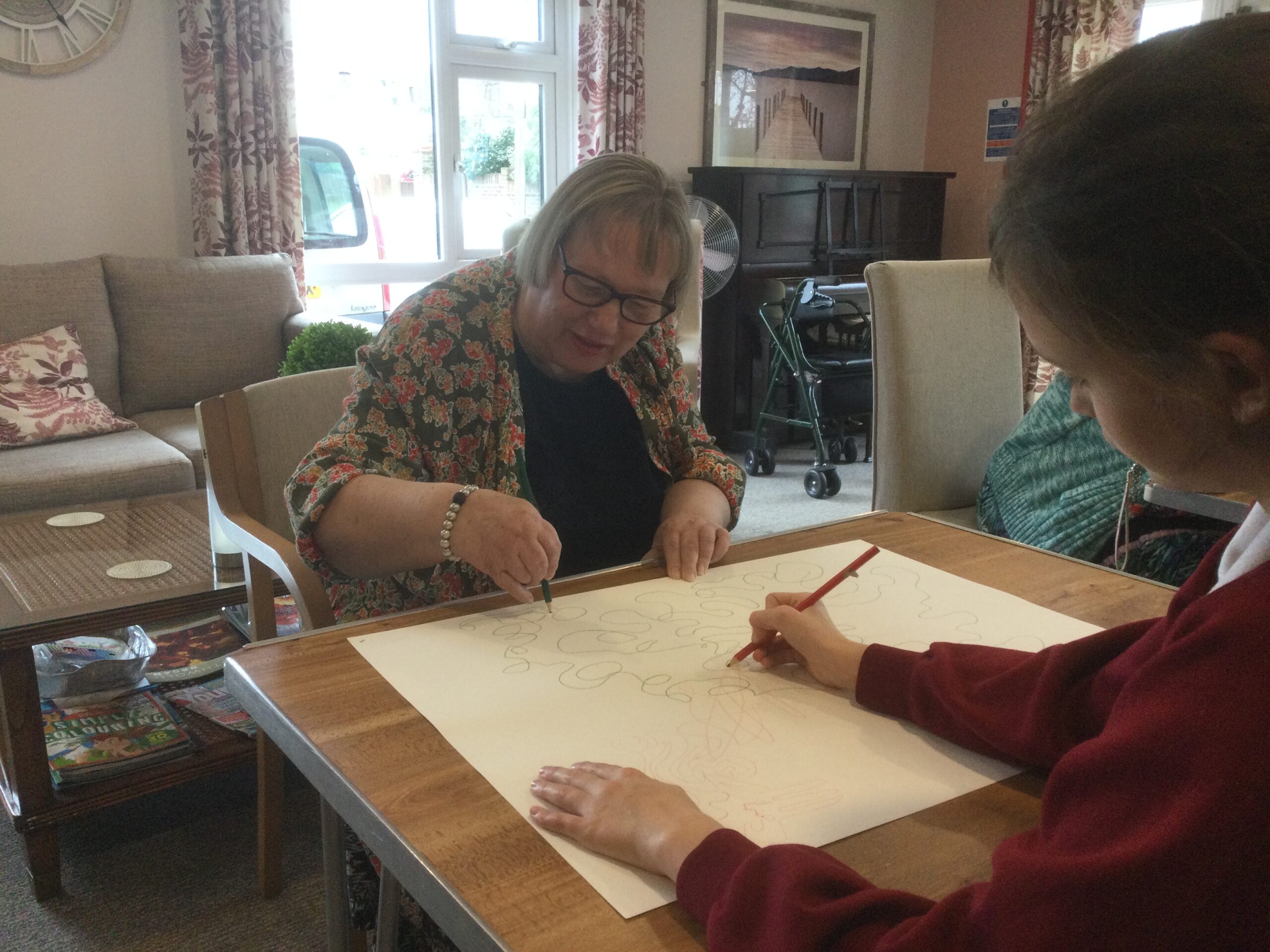 An adult and school girl drawing on a large piece of paper