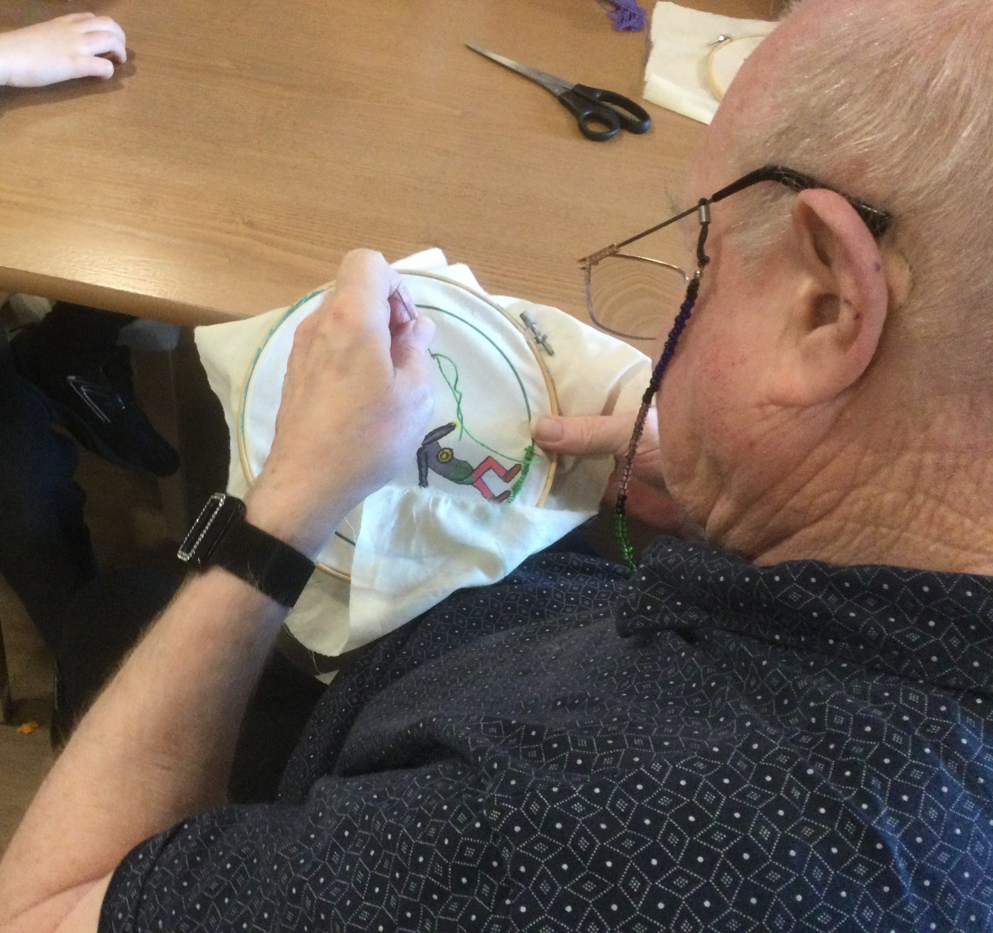 Overhead view of gentleman stitching a picture of a football playher