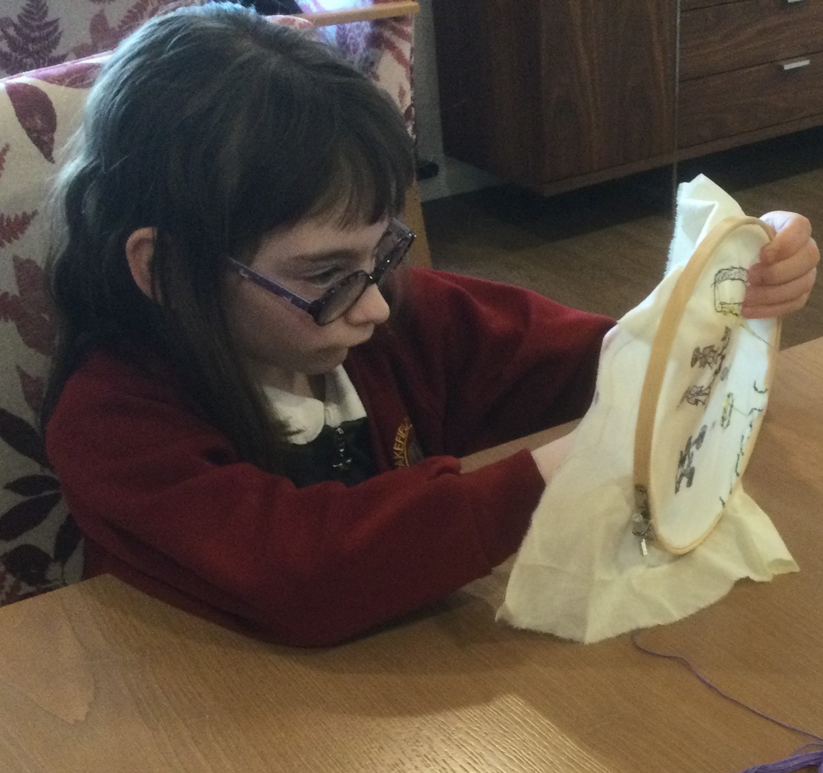 A child sits focused intently on a piece of embroidery she's holding