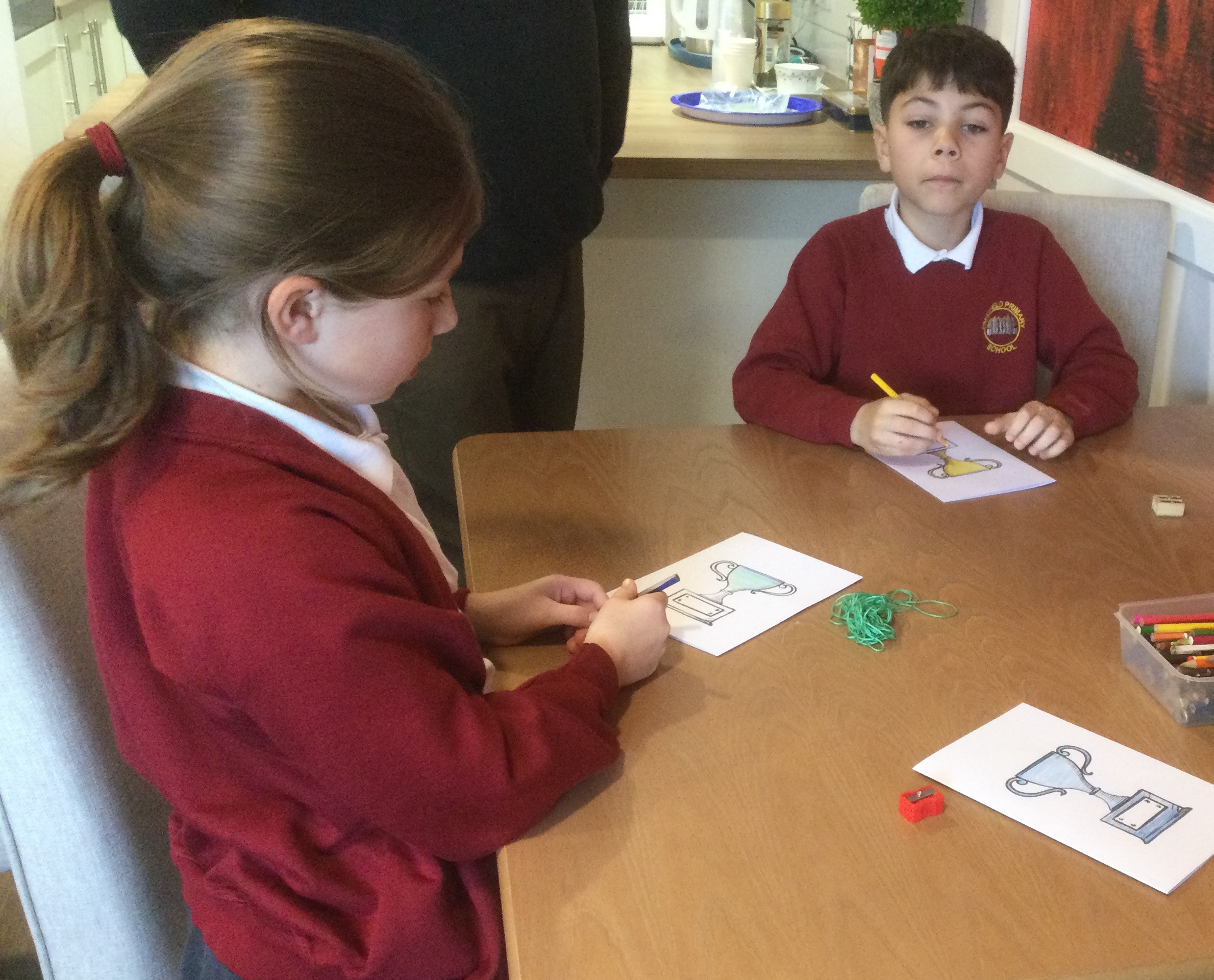 Two school children colouring in their cards