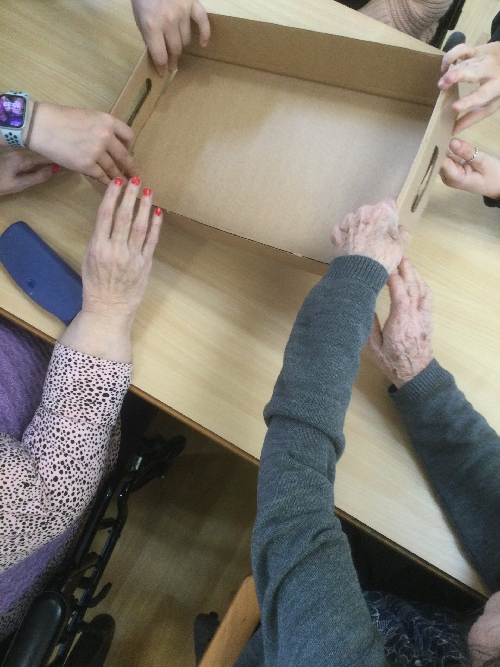 Overhead picture of several pairs of hands assembling a cardboard box
