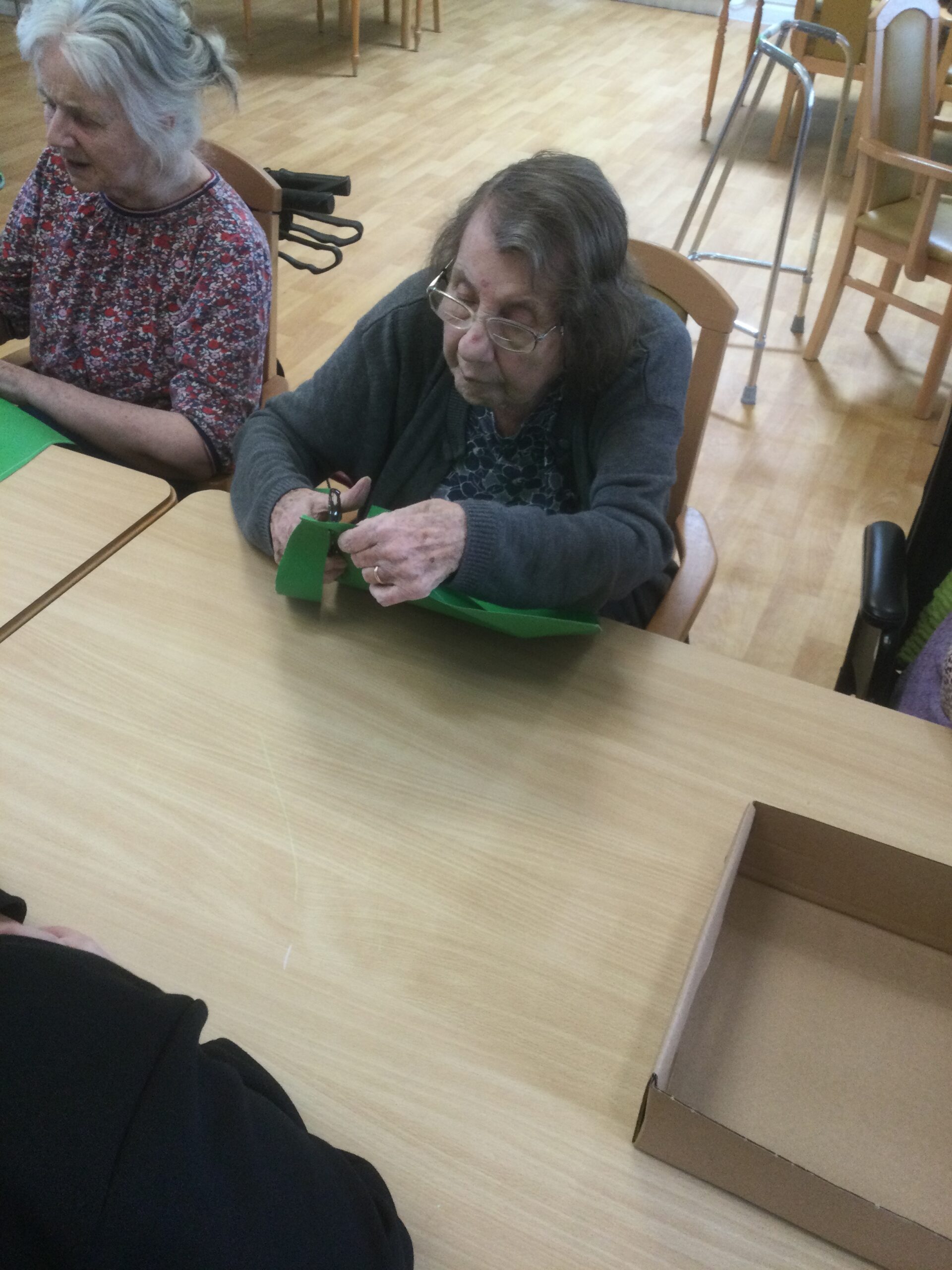 A woman concentrates on cutting a piece of green material