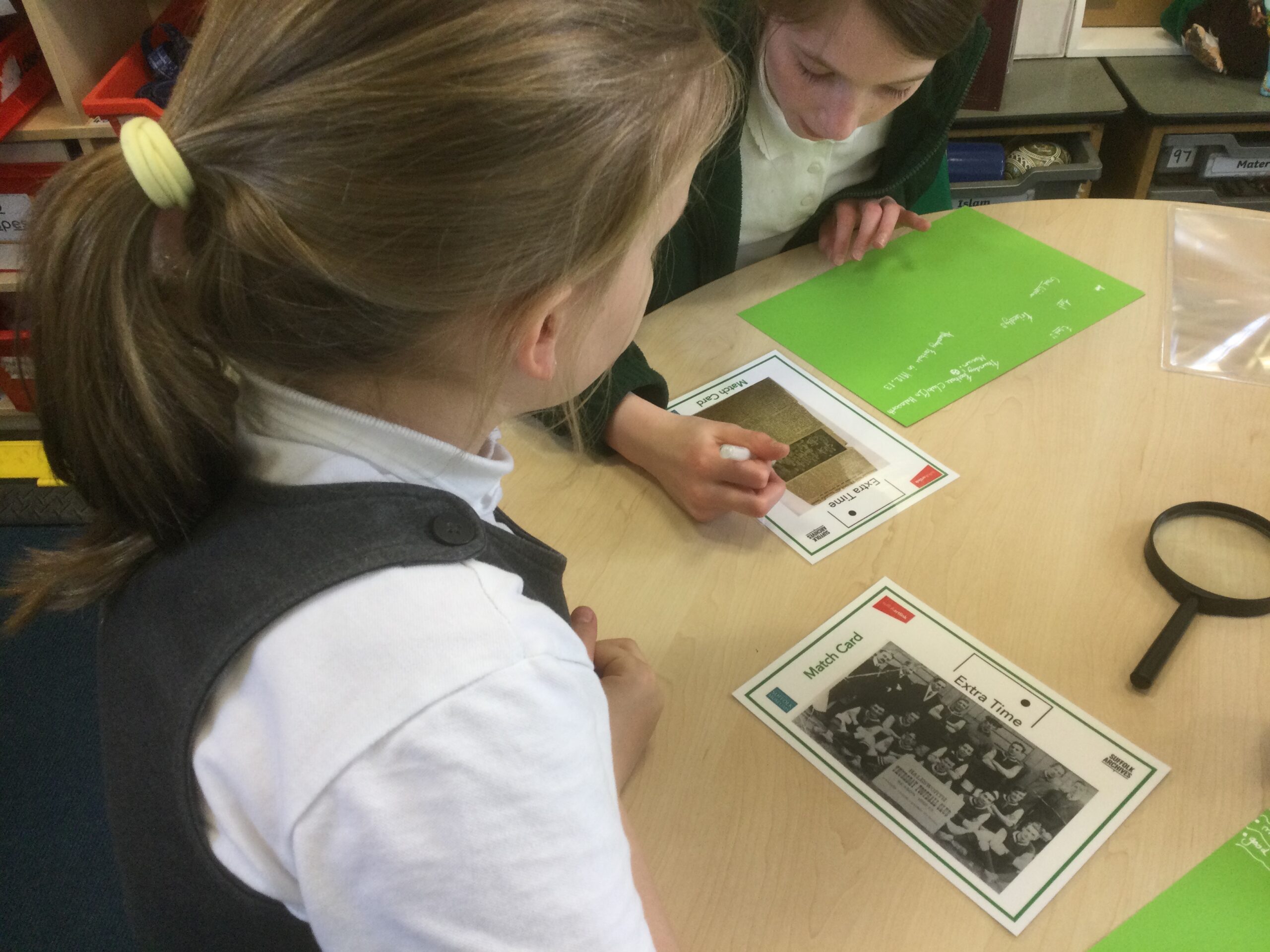 Two school girls studying photographs of a football team and an old press cutting