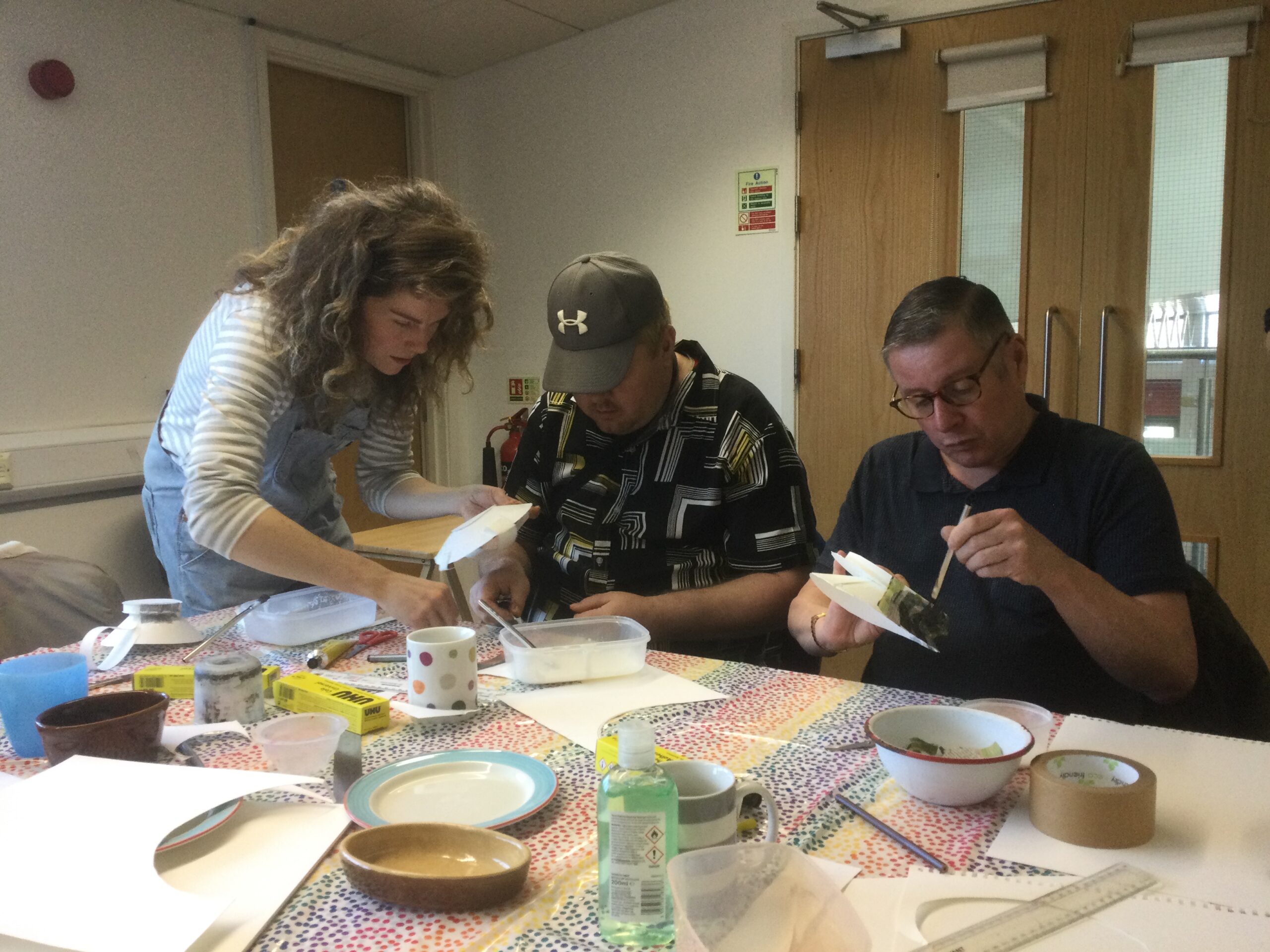 3 people gluing newspaper onto bowl shaped objects