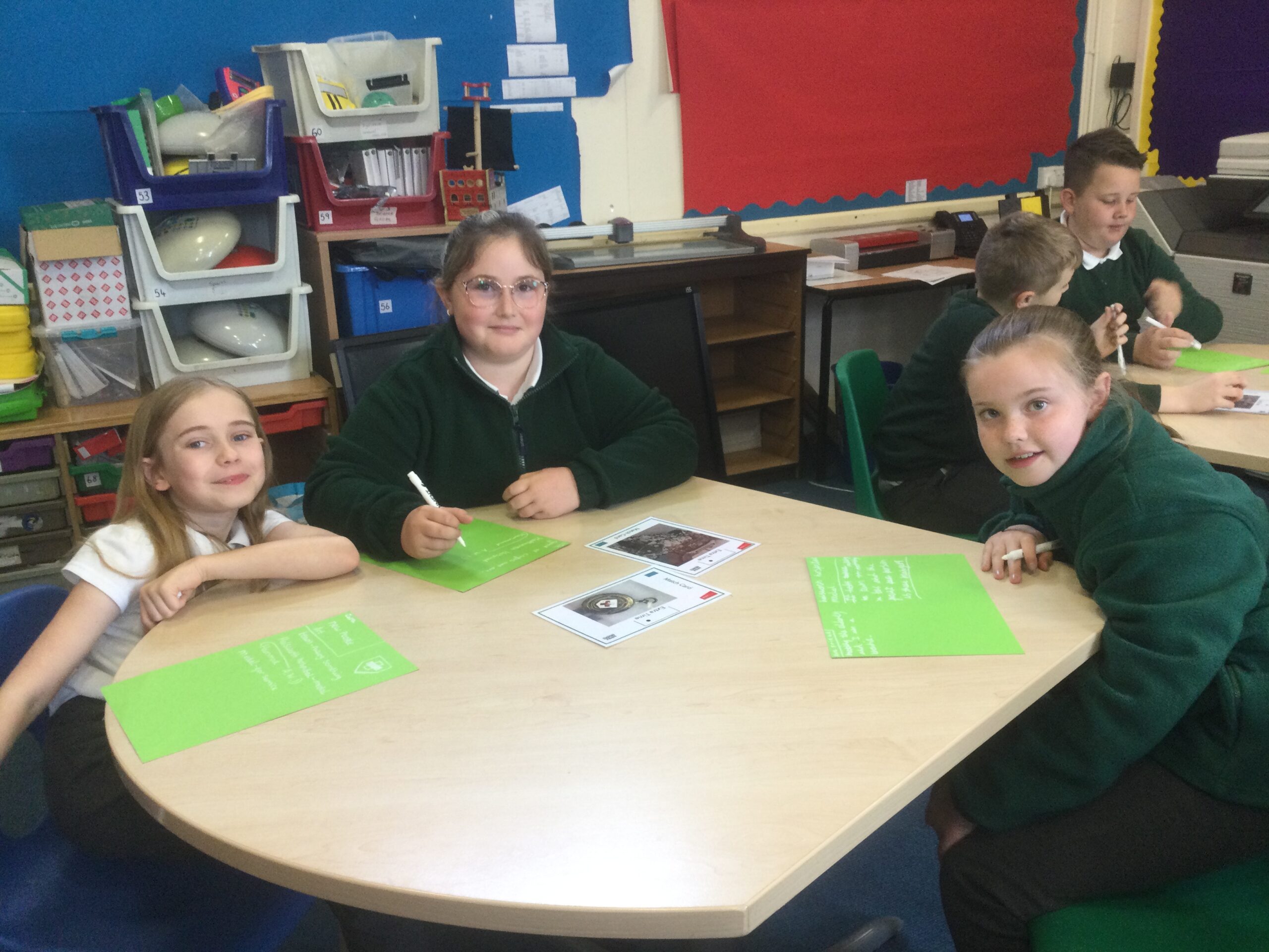 School children studying photographs and making notes on green paper