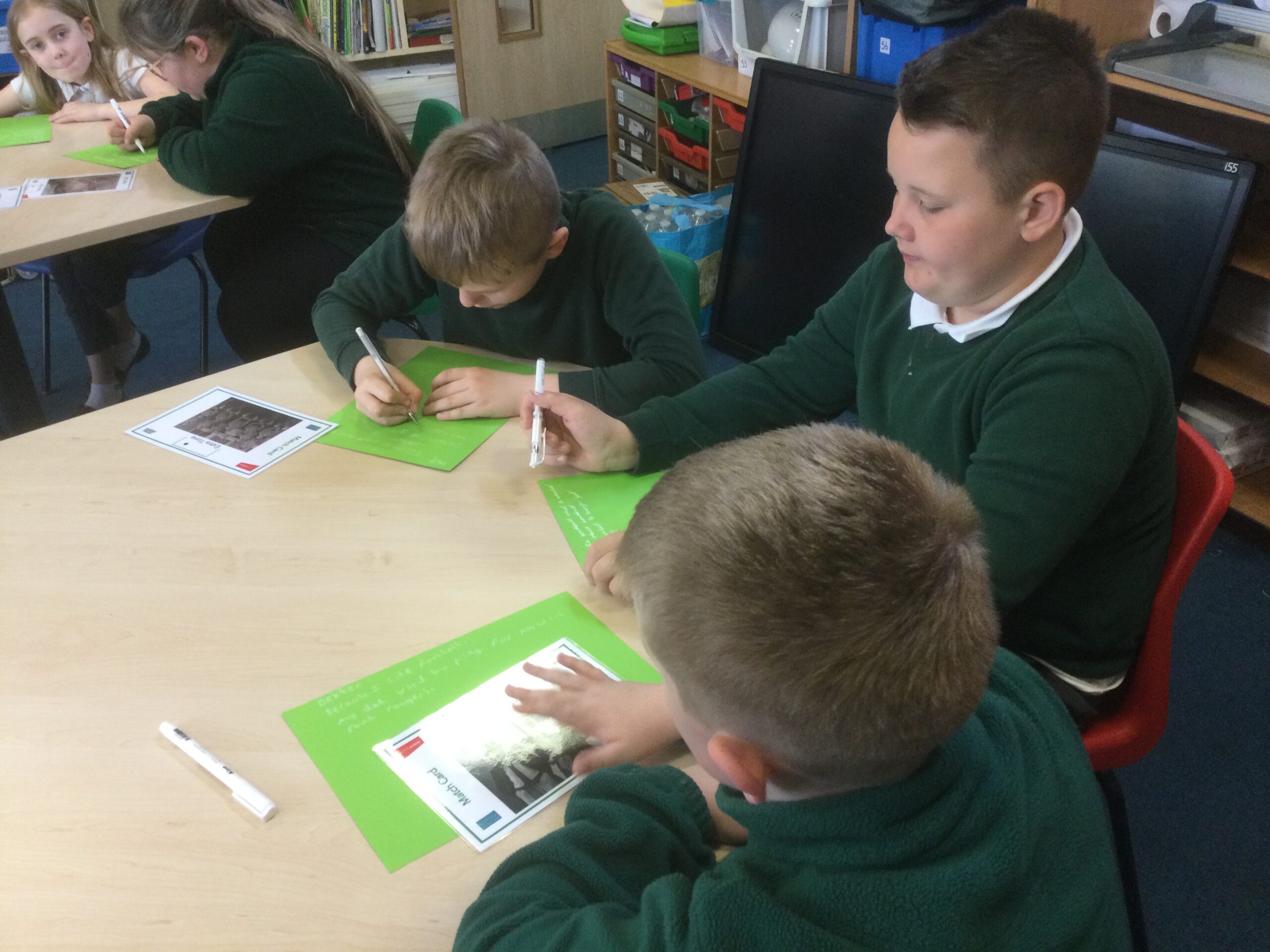 School children studying old photographs and making notes on green paper