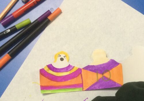 Paper people coloured in orange and purple and various coloured felt tip pens