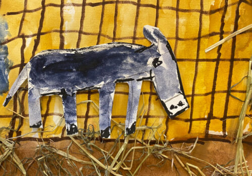 an animated character, a donkey, against a farmyard background, including real straw.
