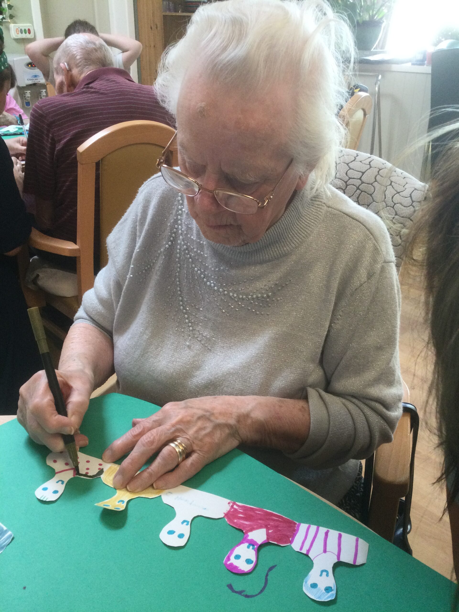 A woman concentrates as she draws an outline around a figure