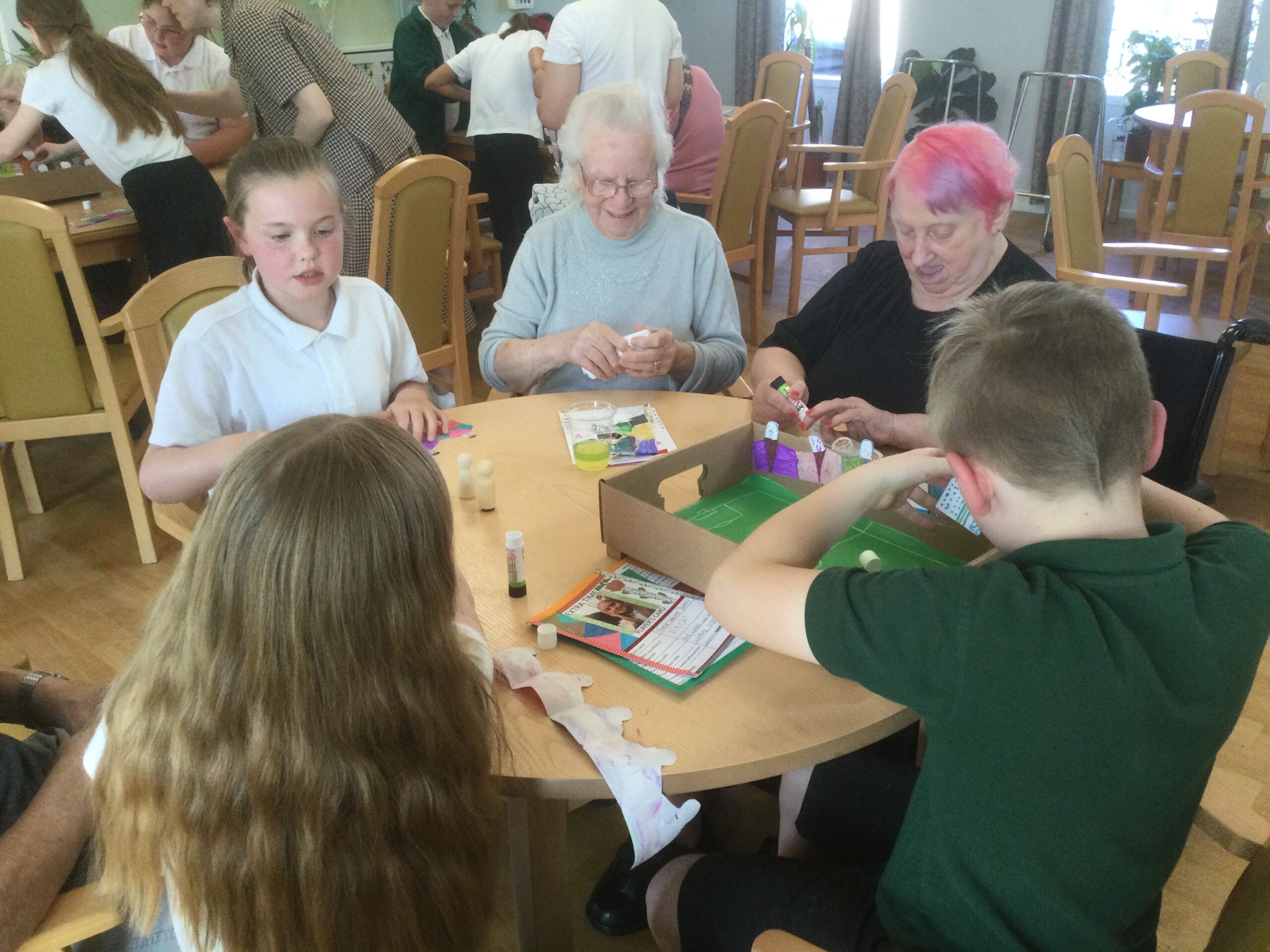 A group of adults and children sticking paper figures to the sides of the box