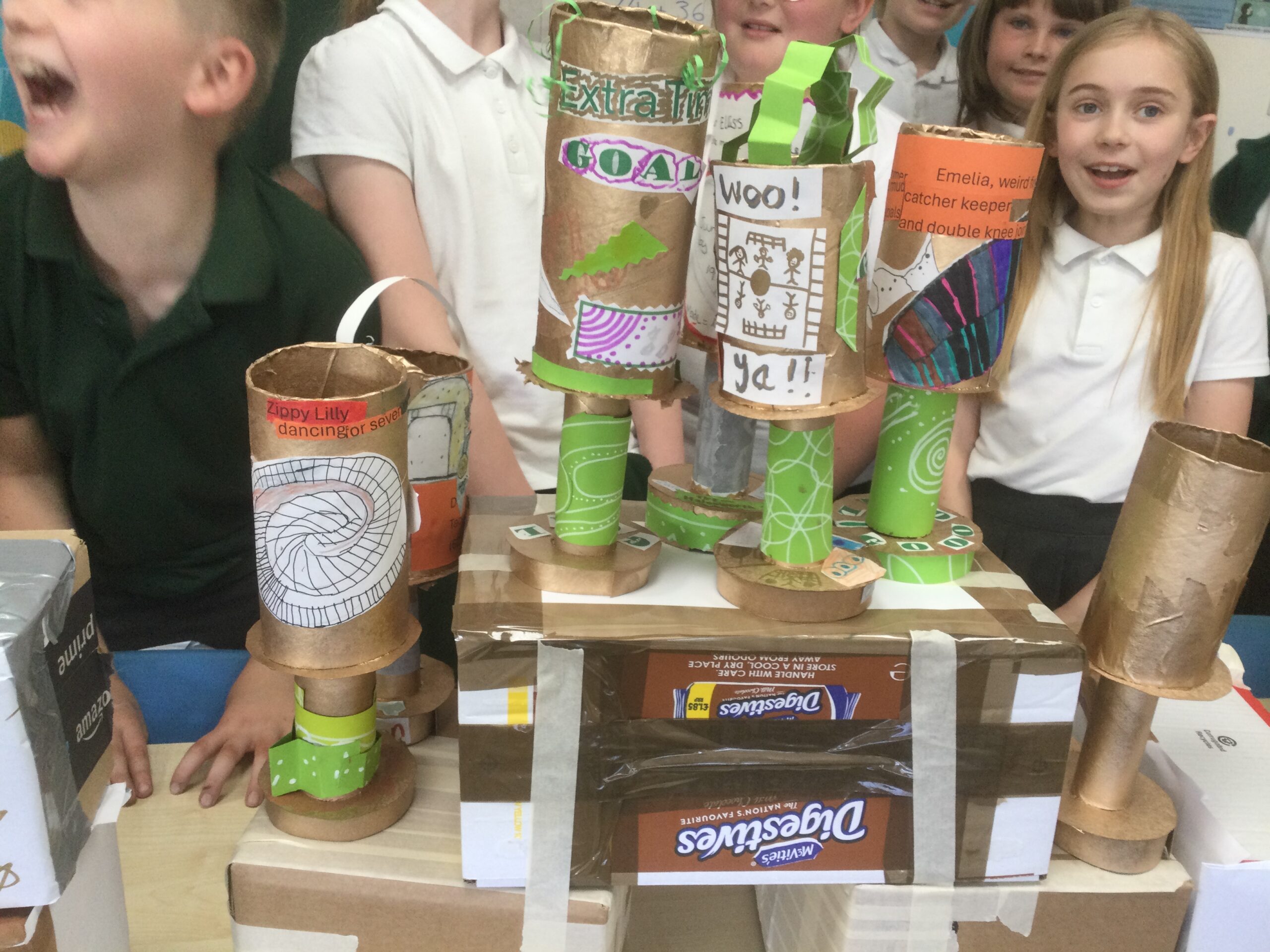 Close up of trophies on cardboard box stands with children behind