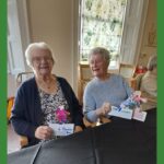 Two women smiling together, holding cardboard football characters