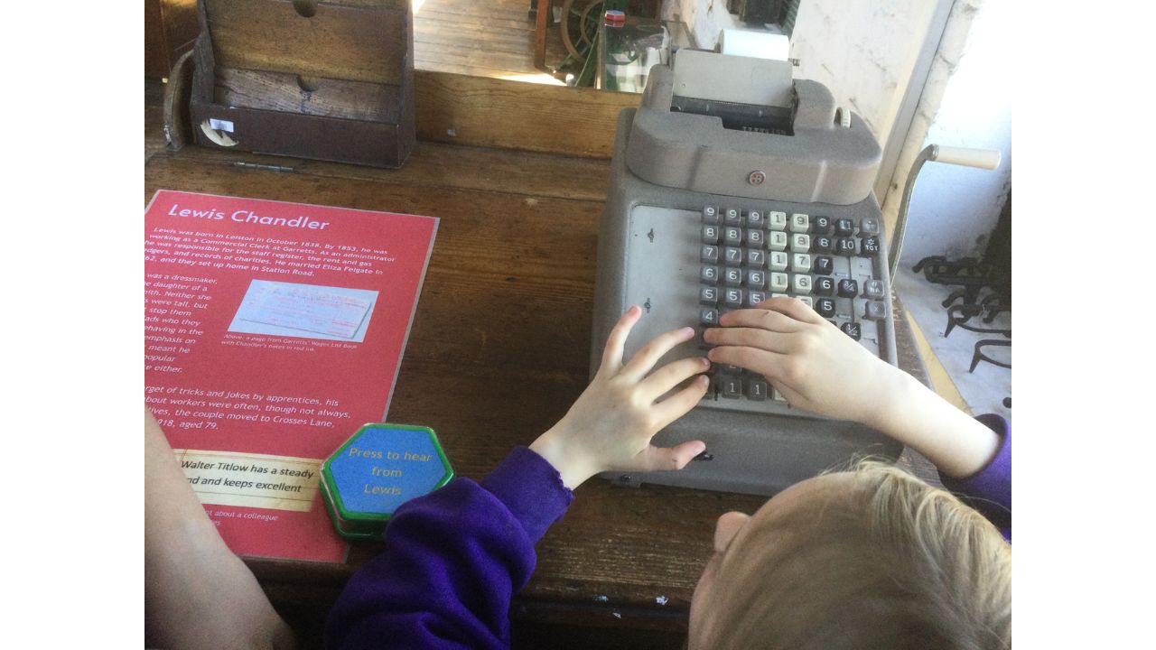 Overhead view of child's hands on an old fashioned adding machine, pressing buttons
