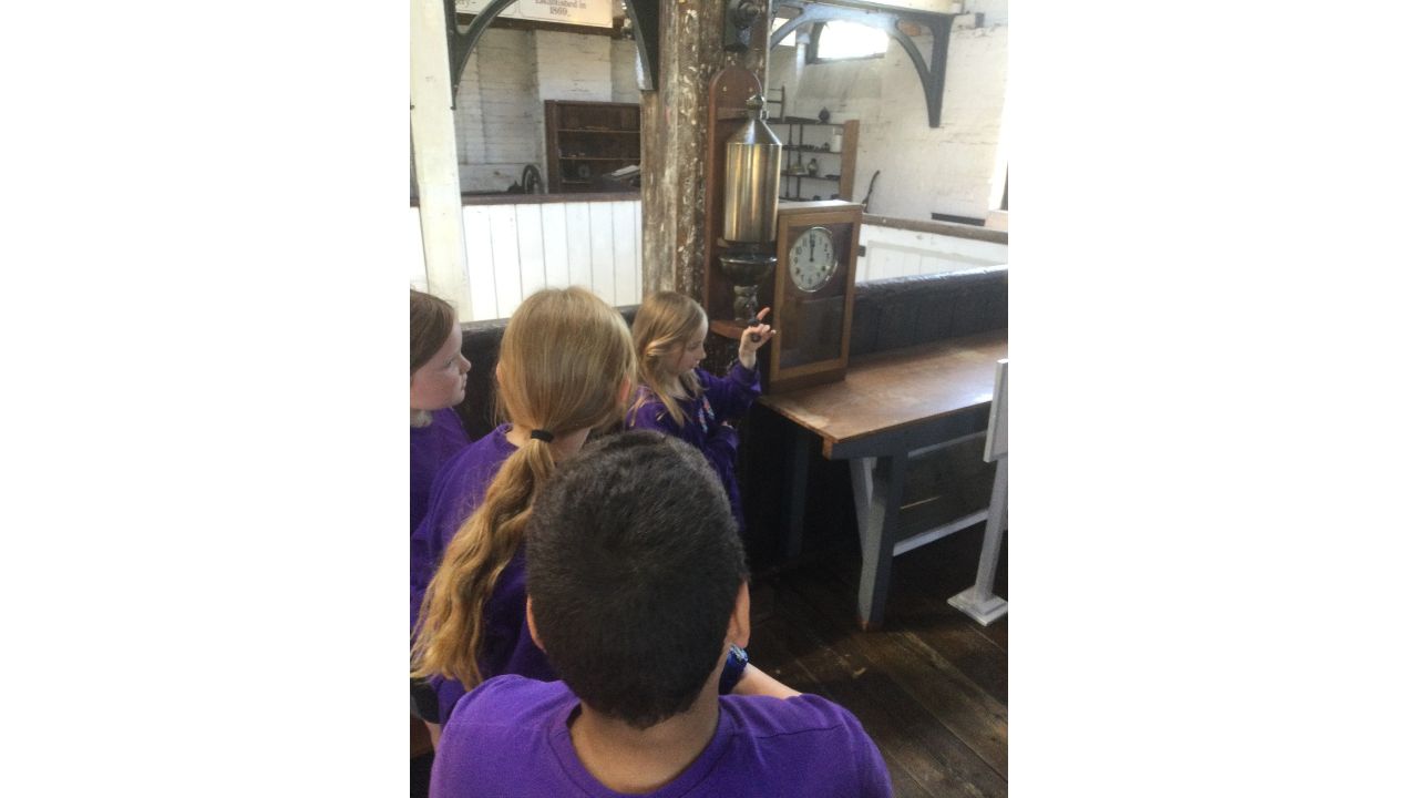Back view of children beside an old fashioned clocking on device and factory whistle