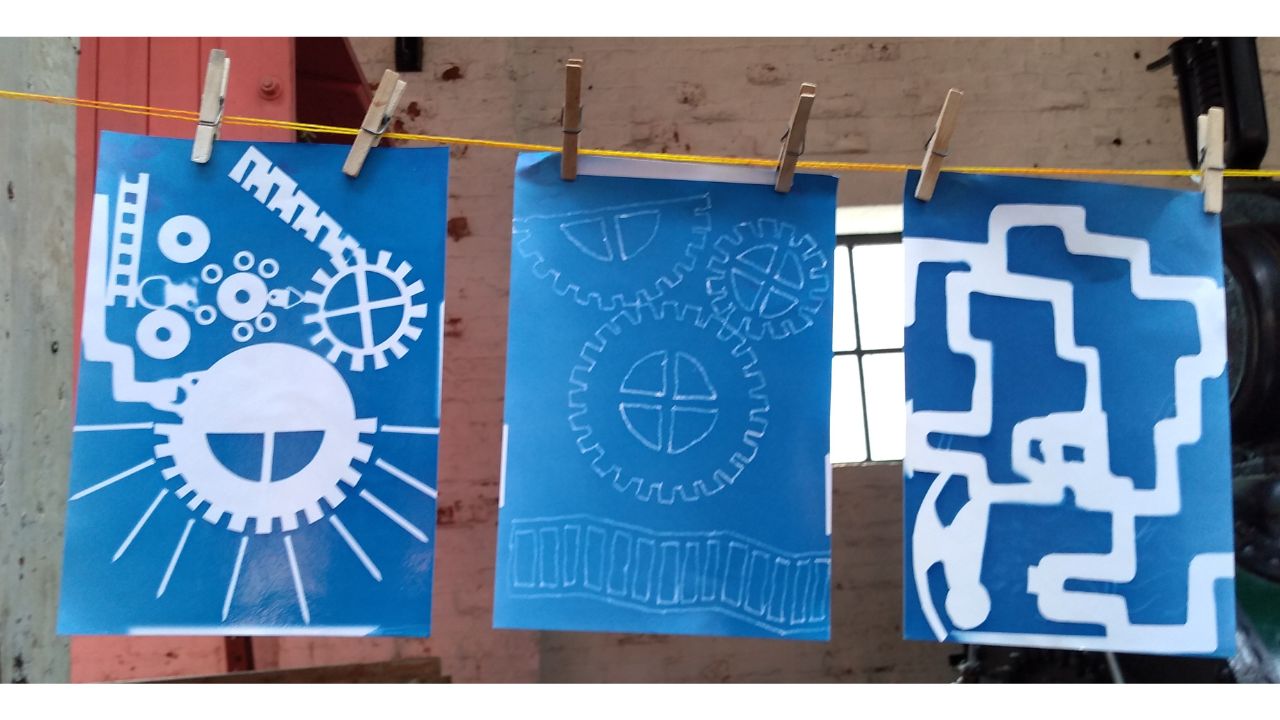 Three blue and white pictures pegged up on a yellow line