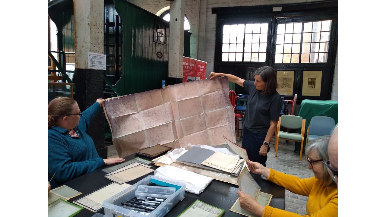 Two adults holding up a huge technical drawing
