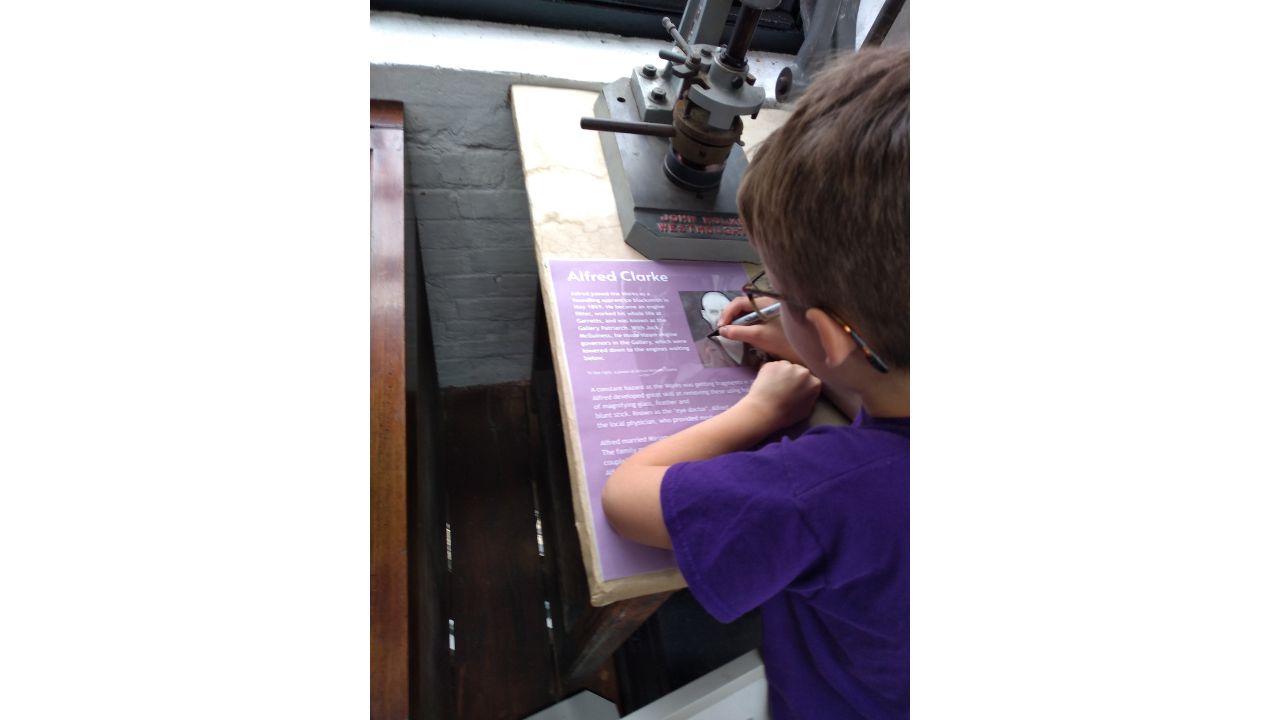 A child uses acetate paper to draw around a picture of a gentleman who worked at Garretts