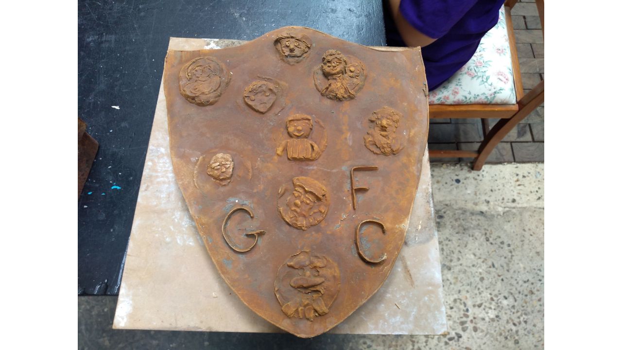 A plaster cast, slightly rusty in appearance, showing individuals in relief and letters GFC Garretts Football Club